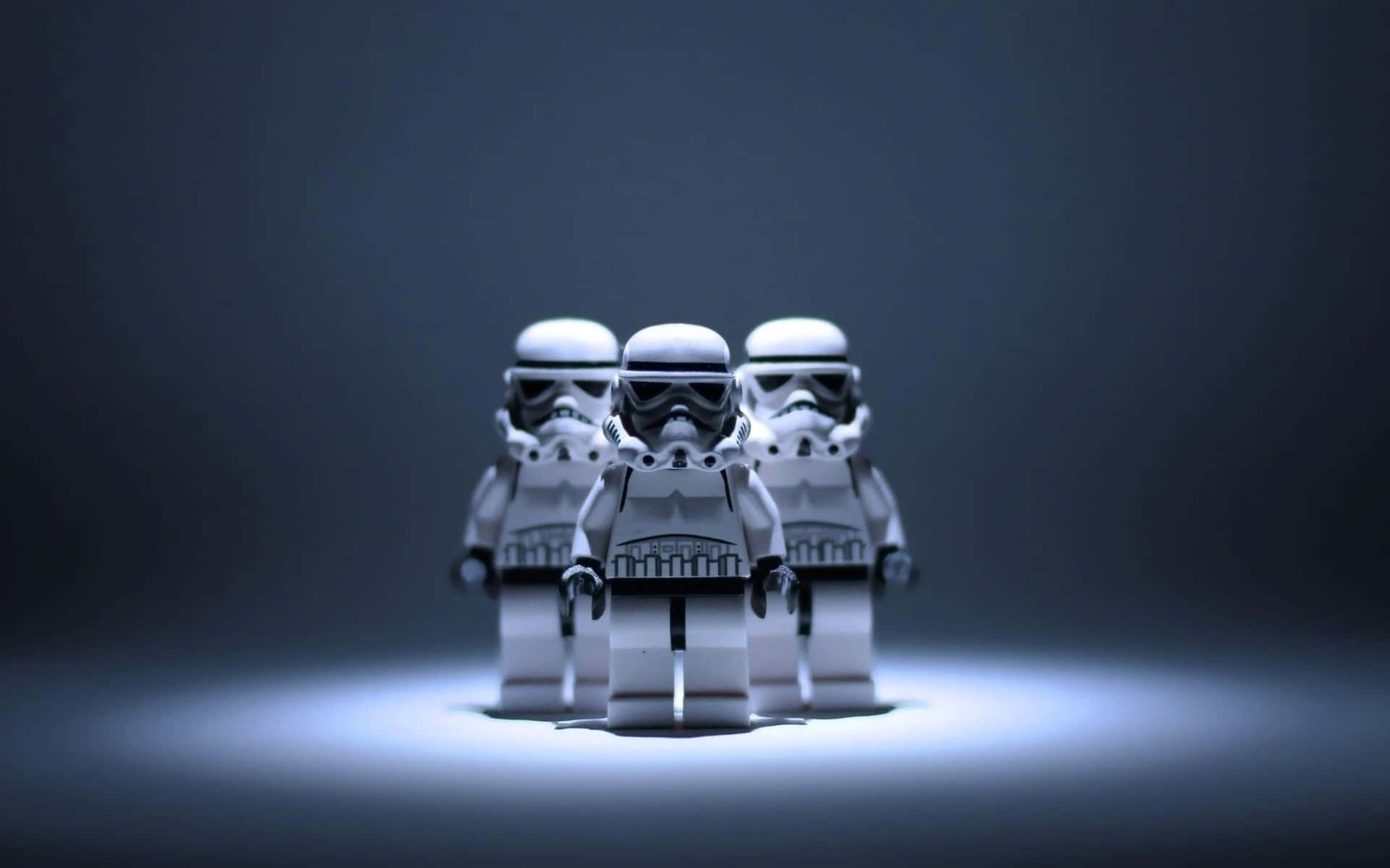  壁紙 — 三個LEGO風暴兵站在聚光燈下，背景為深色漸變，被冷藍色光照亮。