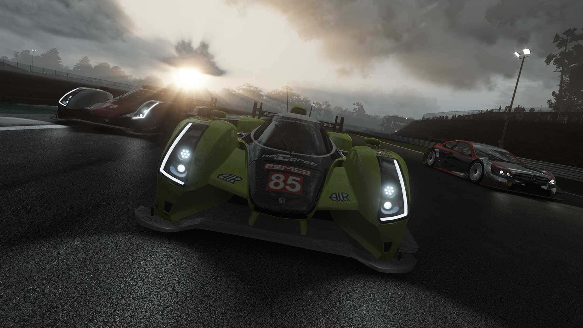 三輛賽車在日出時分於潮濕賽道上疾馳，背景有霧氣繚繞的樹木。 — Project Cars 2 壁紙