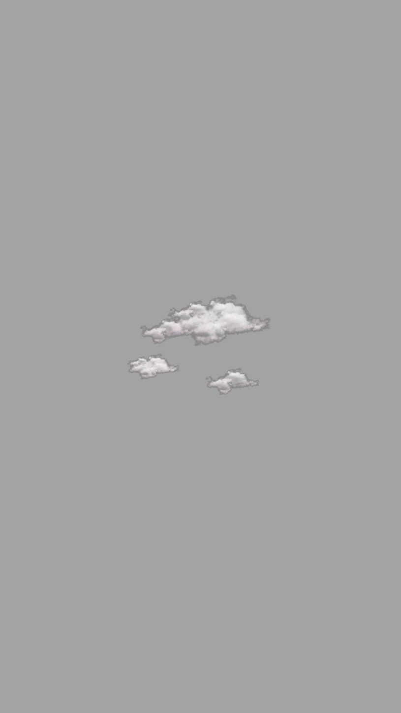 壁紙 — 三朵柔軟的白雲懶洋洋地飄浮在廣闊的柔和灰色天空上。
