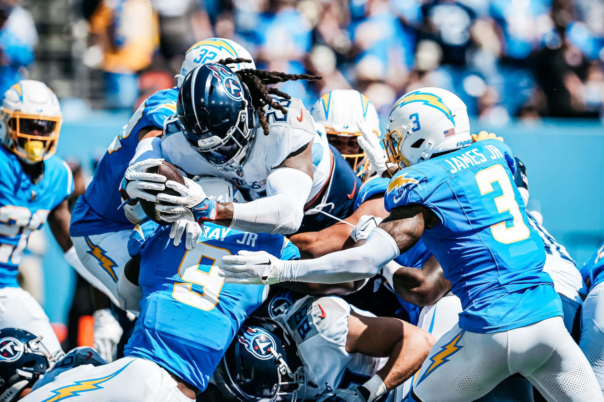  壁紙 — 田納西泰坦隊一名留著辮子頭的球員在激烈的NFL比賽中，被多名洛杉磯電光隊防守球員擒抱時仍緊緊抓住橄欖球。