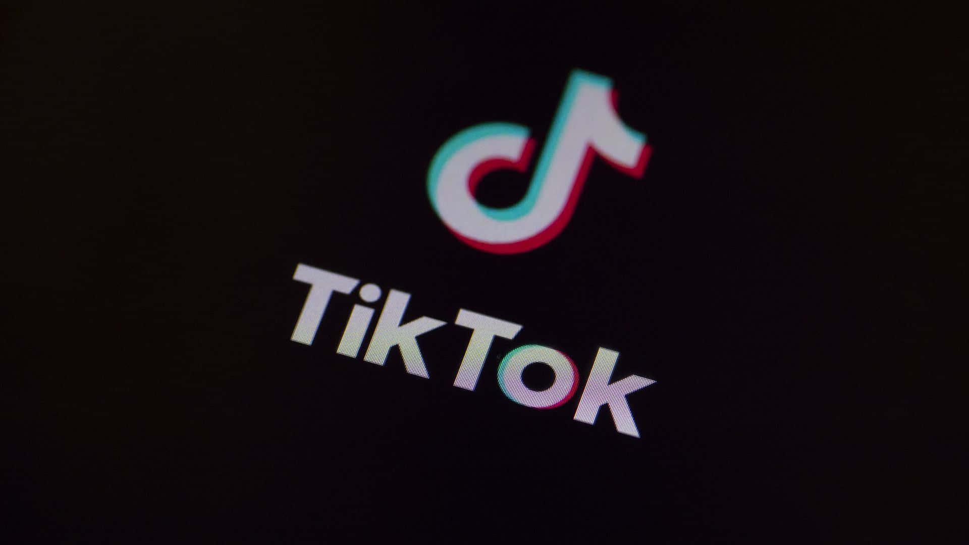 TikTok Icon 桌布 壁紙 — TikTok 標誌在黑暗螢幕背景上發出霓虹粉紅和青色光芒。