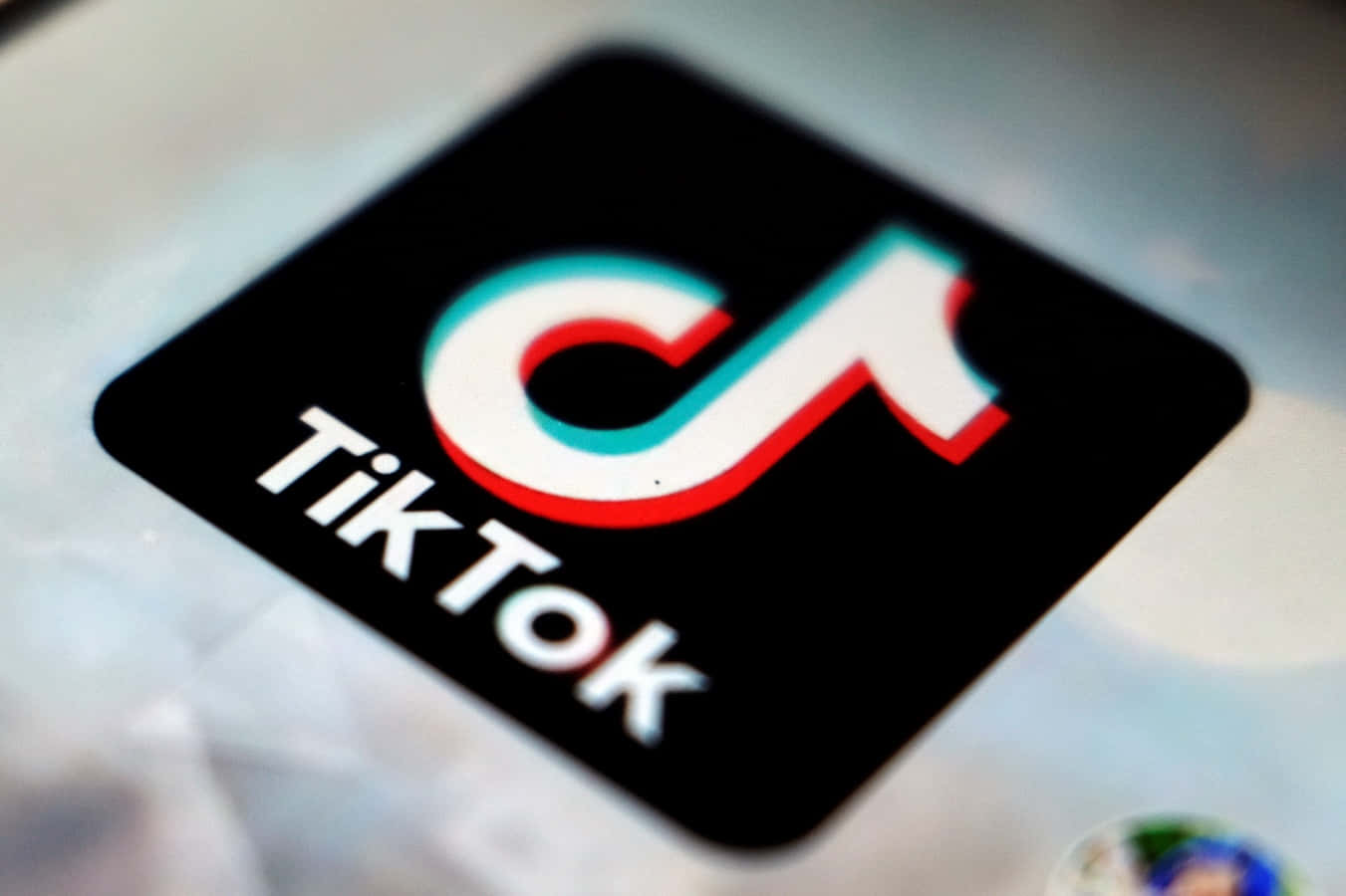 TikTok 動圖 桌布 壁紙 — TikTok應用程式圖標在模糊的智慧型手機螢幕上發出紅色、藍綠色和白色的特寫。