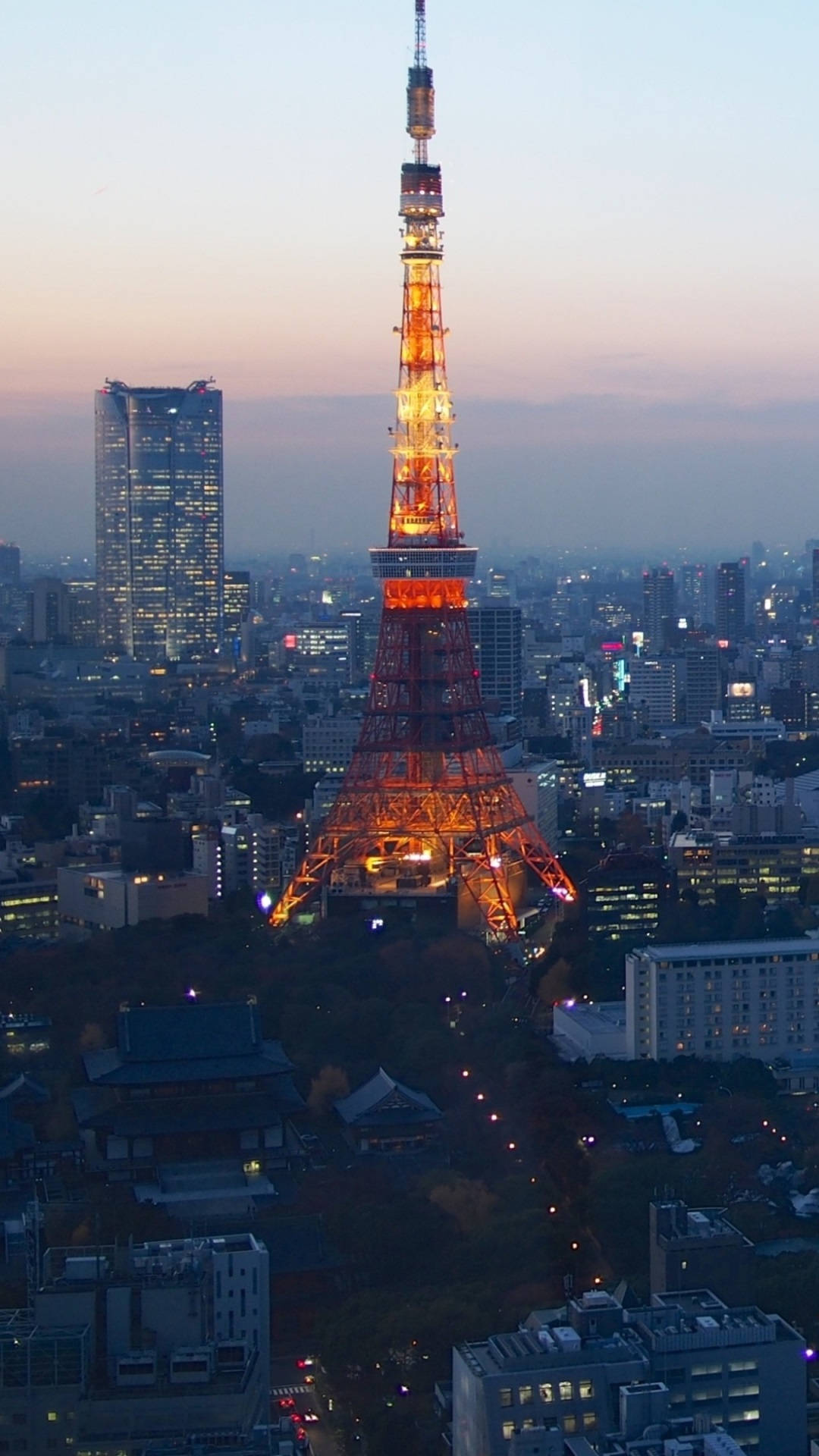 東京鐵塔在黃昏時亮起，城市燈光在下方閃爍。 — 東京 壁紙