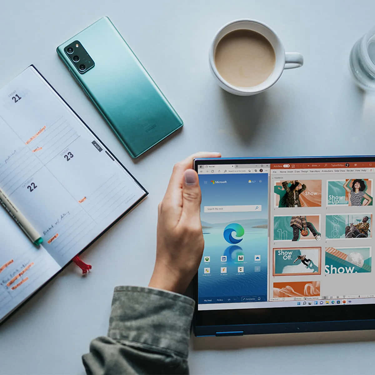 手拿著平板電腦，Microsoft Edge 已打開，旁邊有日曆、電話、咖啡和水在桌子上。 — Microsoft Teams 壁紙
