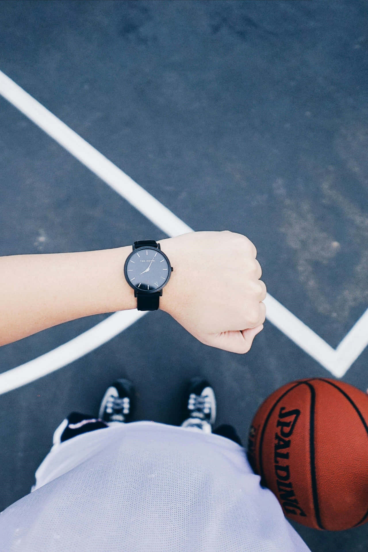  壁紙 — Top-down view of a person's wrist with a black watch and clenched fist on a basketball court with a Spalding ball nearby.
