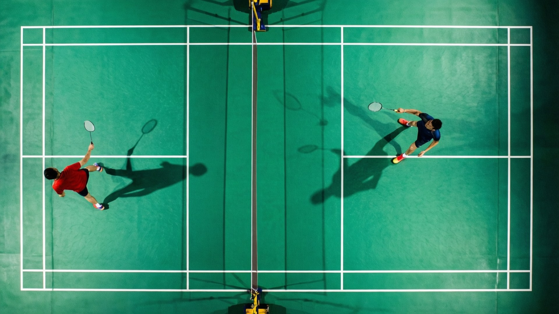 Court from Above 壁紙 — 從上方俯瞰兩名羽球運動員在充滿活力的綠色球場上比賽，球場上有清晰的白色線條。