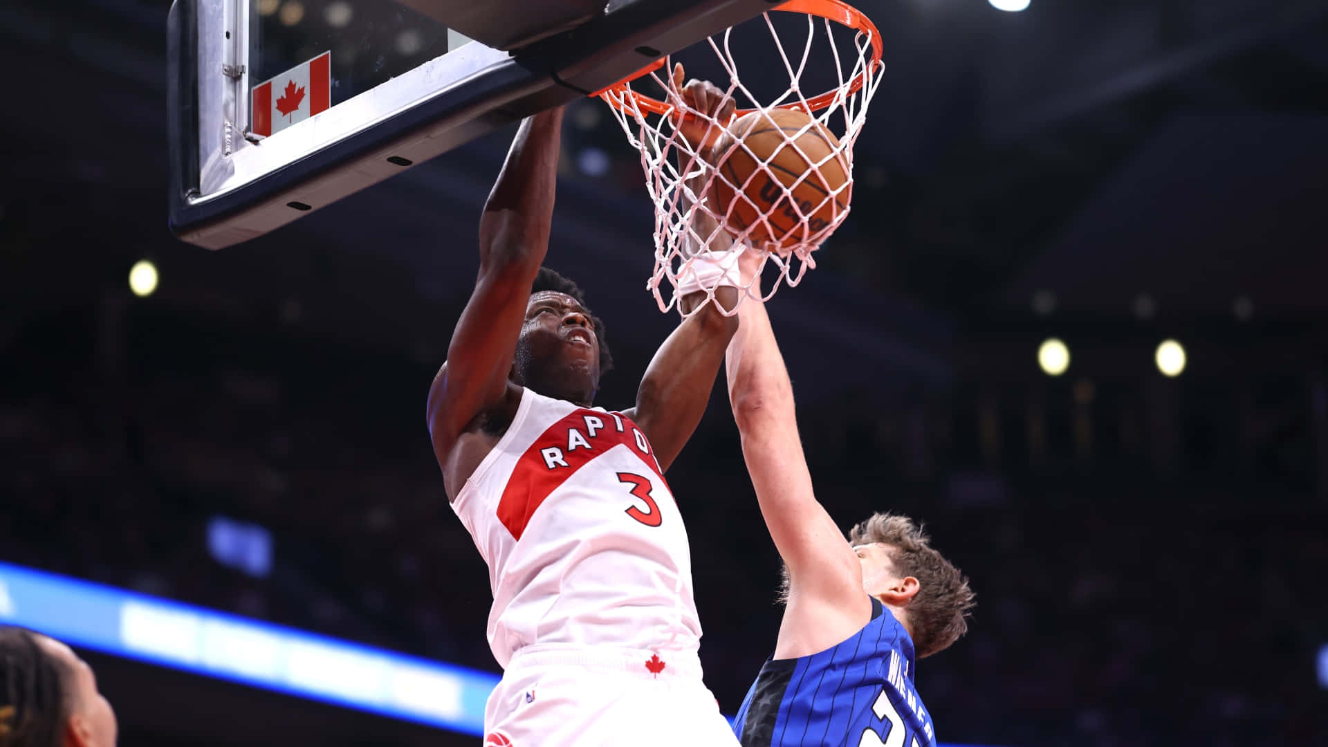 多倫多暴龍隊球員在場館中越過防守球員灌籃。 — NBA 壁紙
