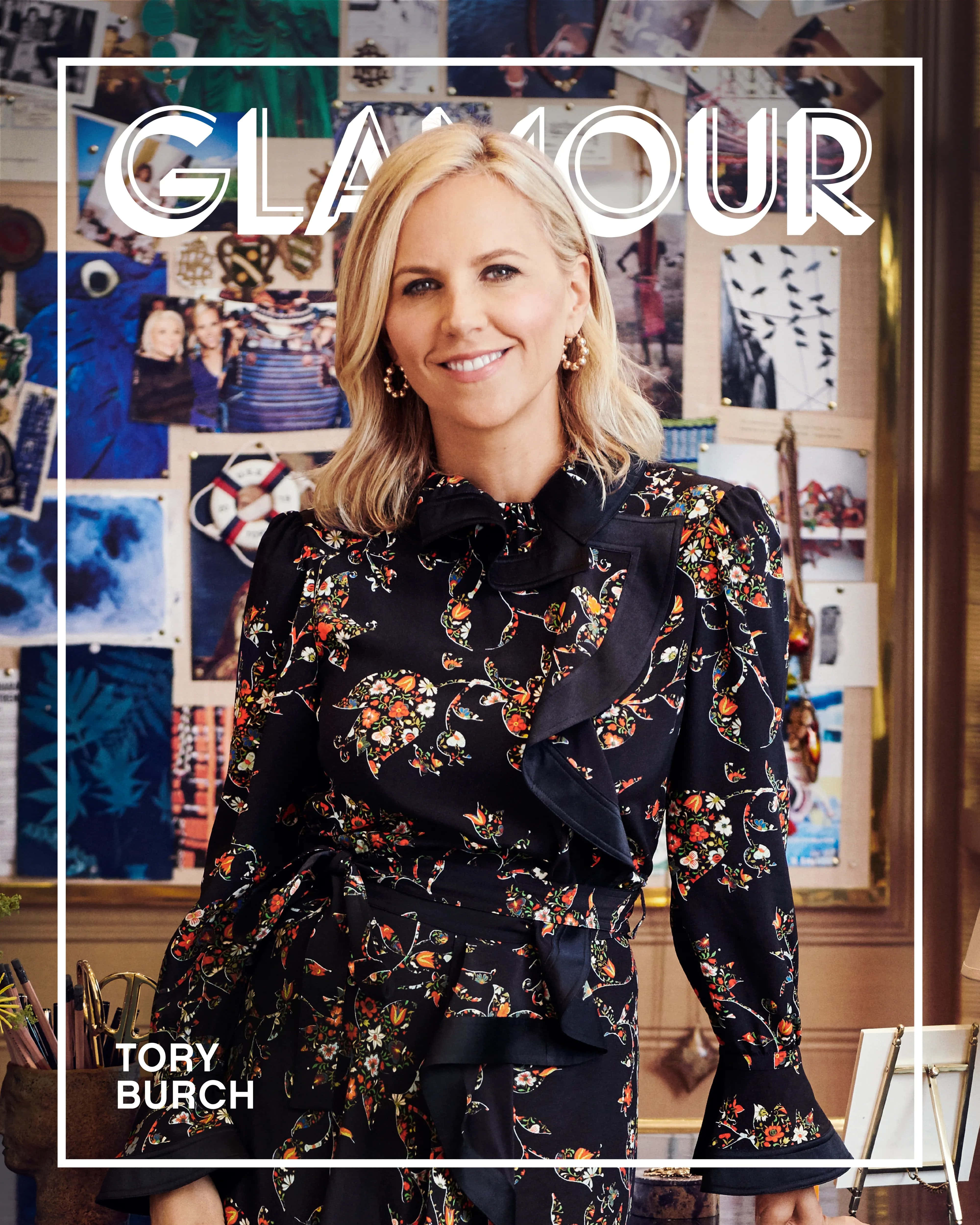 Tory Burch 桌布 壁紙 — Tory Burch 身穿花卉印花連衣裙，在充滿活力的拼貼牆前溫暖微笑，牆上疊加著 'GLAMOUR' 文字。
