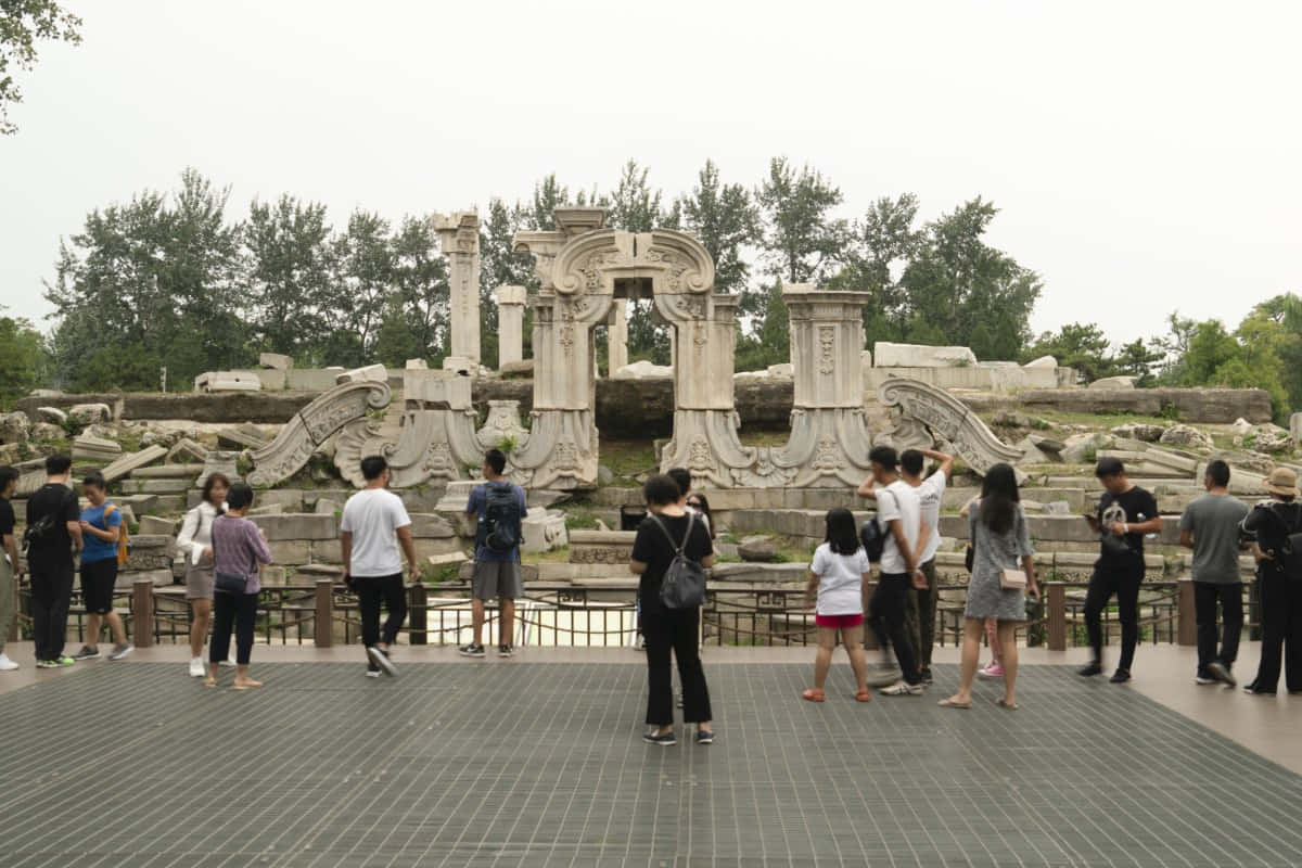 訪客在多雲的日子裡在公園裡走過古老的石頭廢墟。 — 中國 壁紙