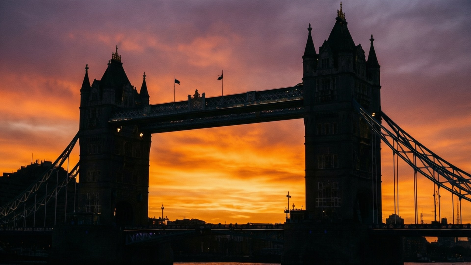 Tower Bridge Sunset Silhouette 壁紙 — 倫敦塔橋在火紅橙色和紫色的日落天空襯托下，呈現出黑暗的剪影。