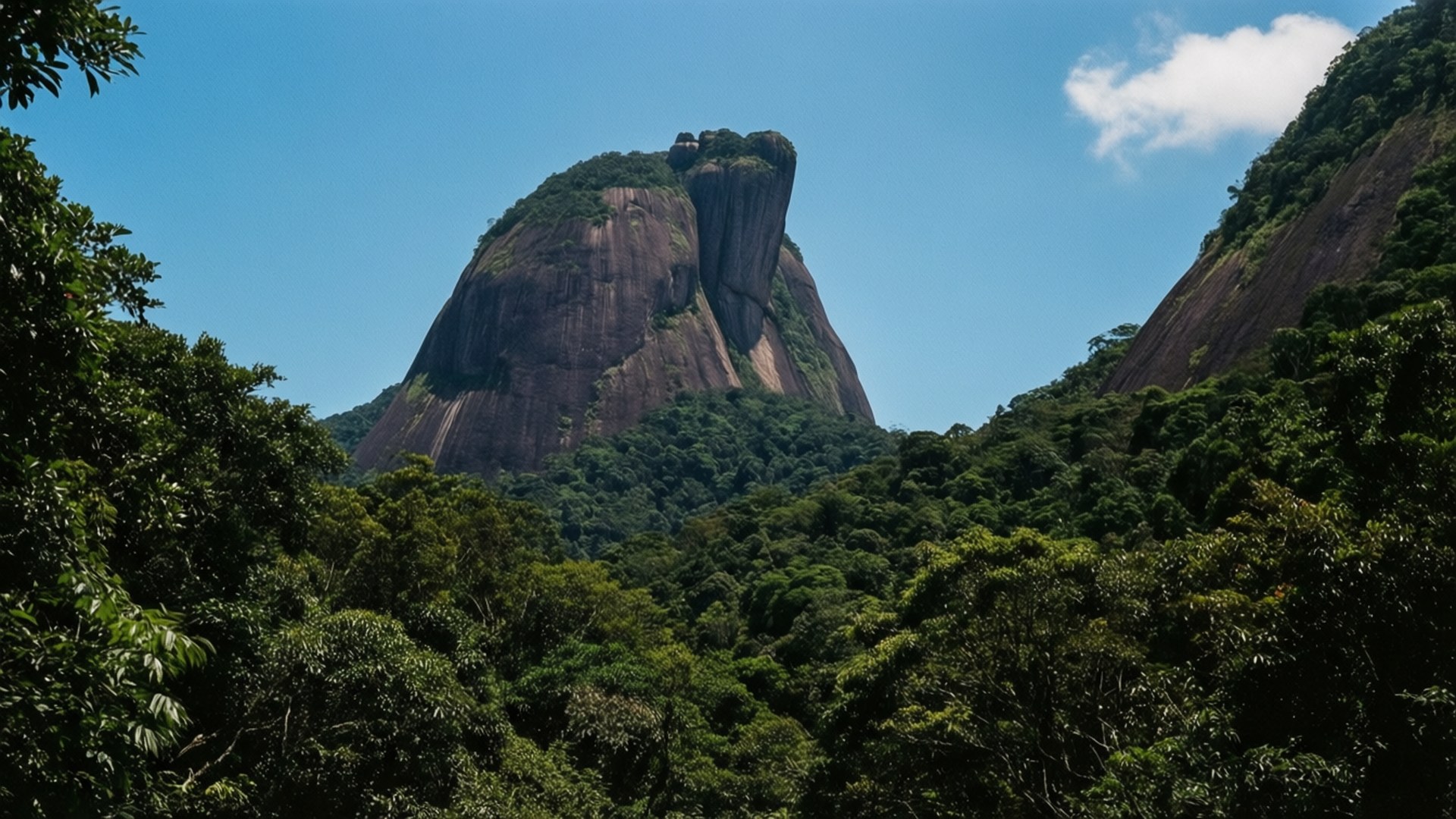 Pedra da Gávea Monolith 壁紙 — 一座高聳的紅褐色花崗岩巨石，在晴朗的藍天和一朵白雲下，雄偉地穿過茂密的綠色叢林。