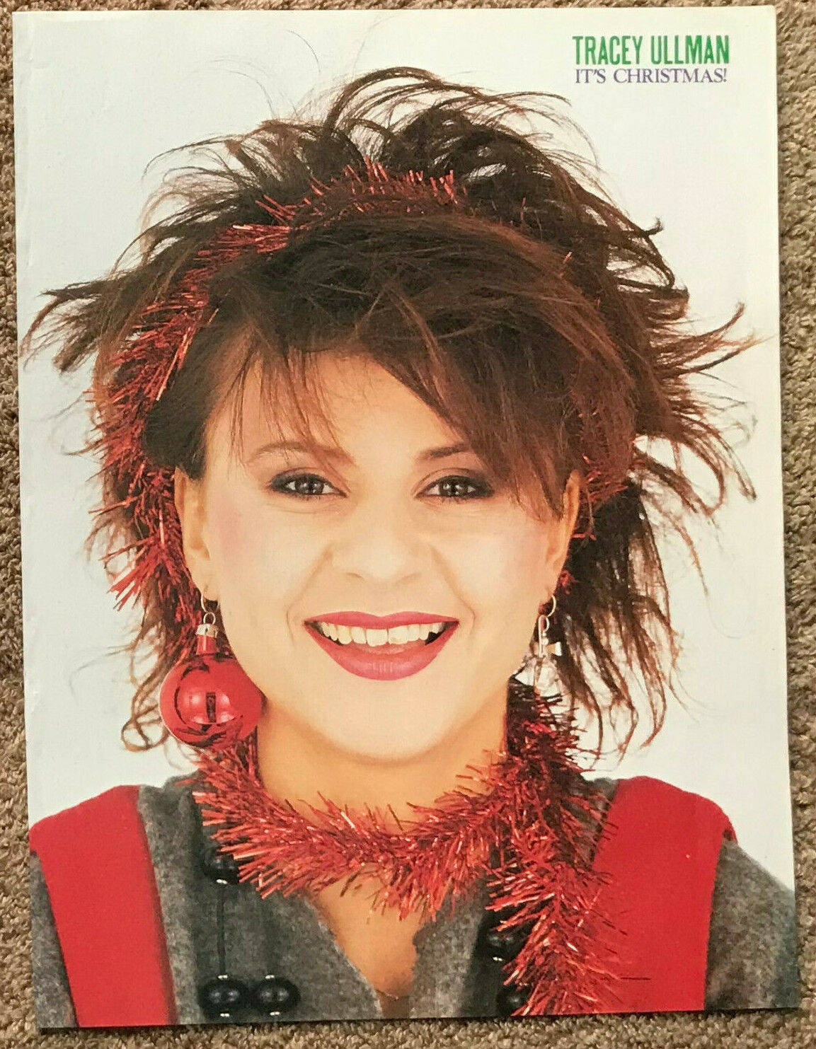 Singer 桌布 壁紙 — Tracey Ullman 在純白背景前，頭髮和脖子上掛著紅色閃粉，燦爛地微笑。