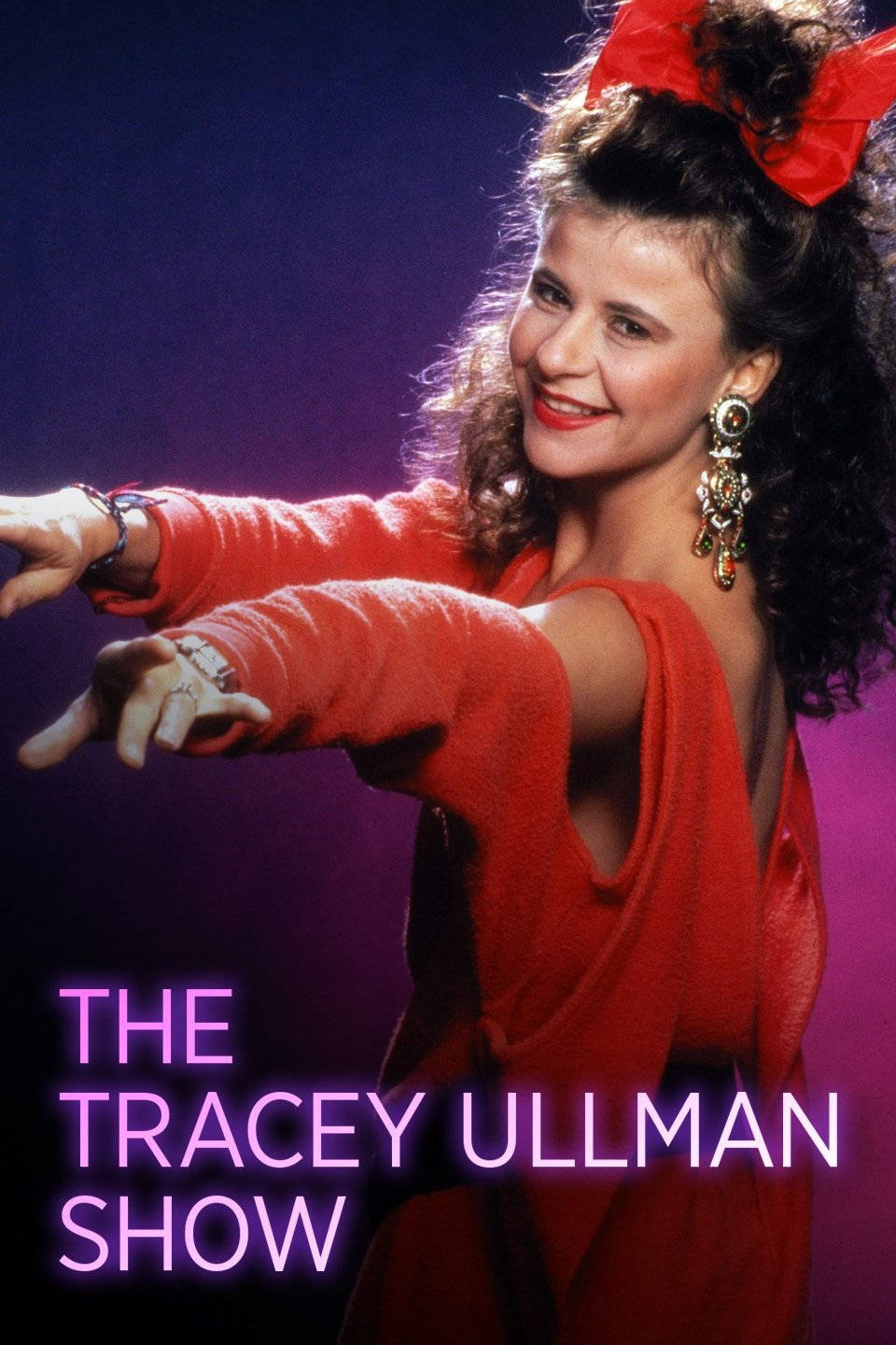 Actress HD 桌布 壁紙 — Tracey Ullman 身穿鮮紅色服裝和蝴蝶結，在紫色工作室燈光下動感微笑。