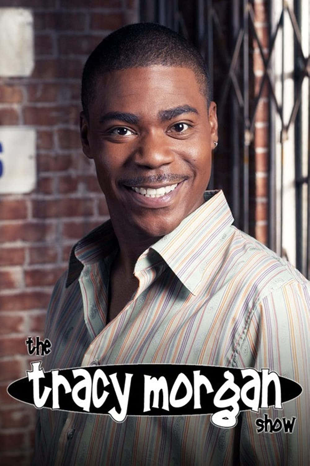 Tracy Morgan 桌布 壁紙 — Tracy Morgan 穿著條紋襯衫，在身後有鐵窗的磚牆前溫暖地微笑。
