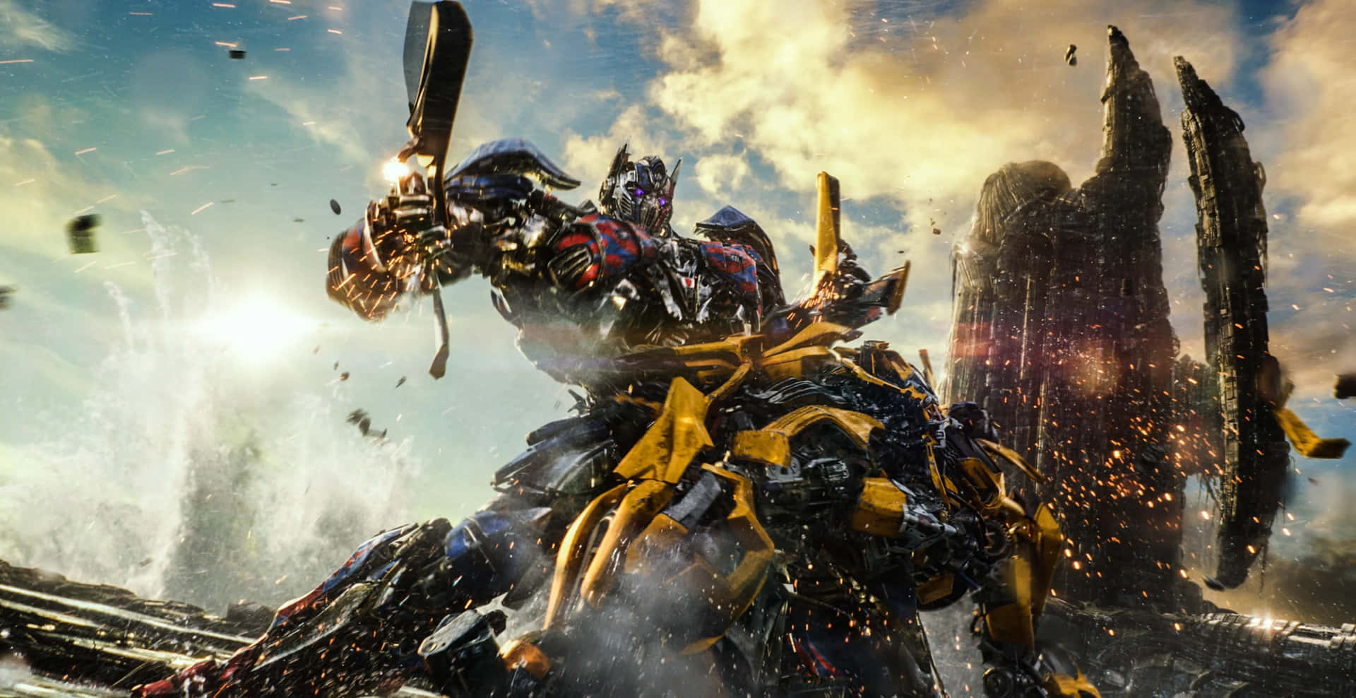 變形金剛 桌布 壁紙 — Transformers Optimus Prime 和 Bumblebee 在明亮的陽光下，於崩塌的摩天大樓和飛揚的碎片中展開激烈戰鬥。