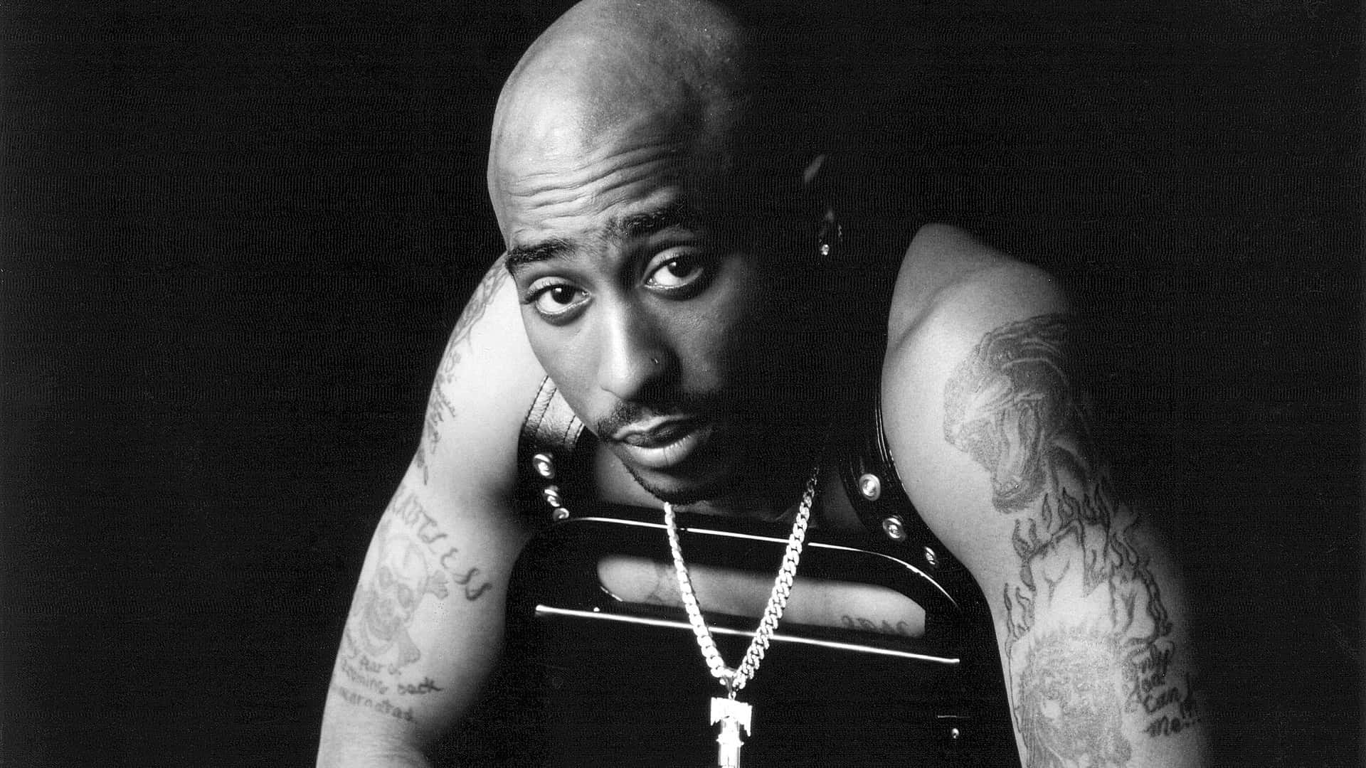tupac 桌布 壁紙 — Tupac Shakur 在黑色背景前，手臂上可見刺青，以黑白肖像照中強烈凝視。