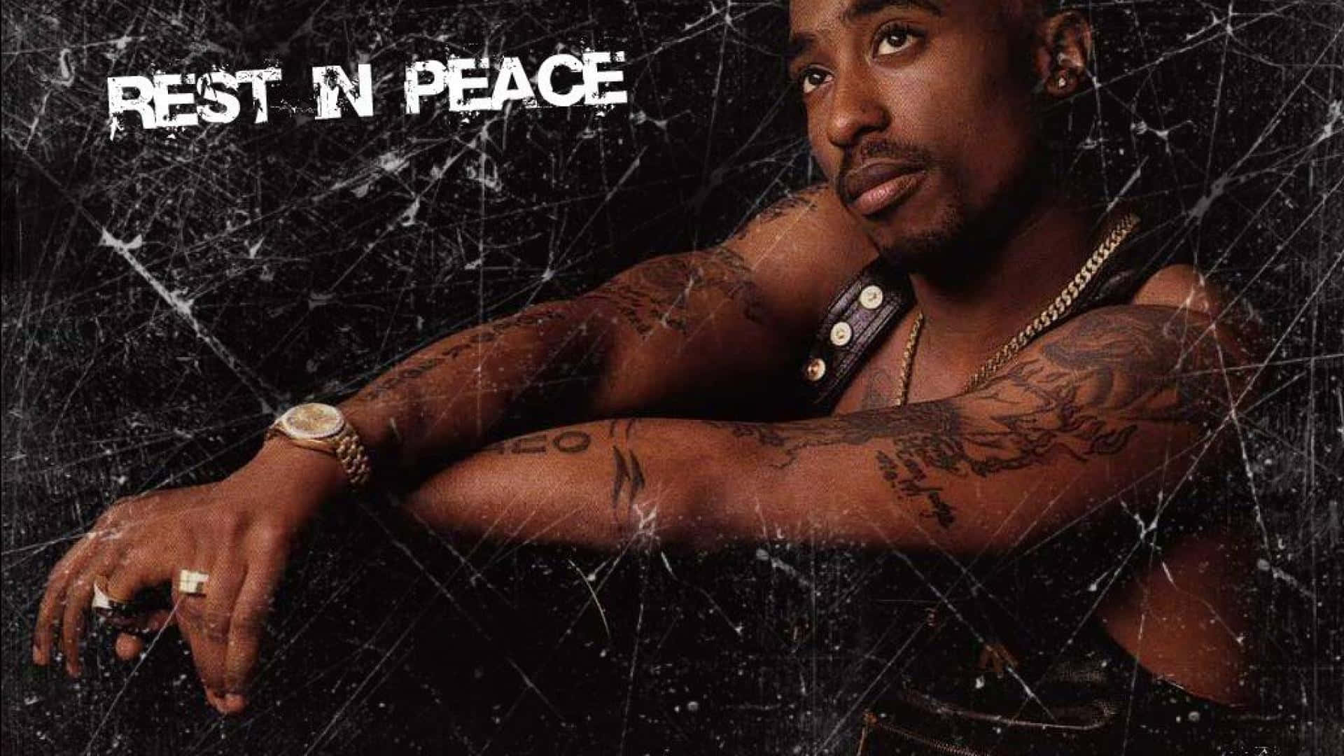 tupac 桌布 壁紙 — Tupac Shakur 展示刺青手臂，背景為裂紋黑色，並帶有 'REST IN PEACE' 文字。
