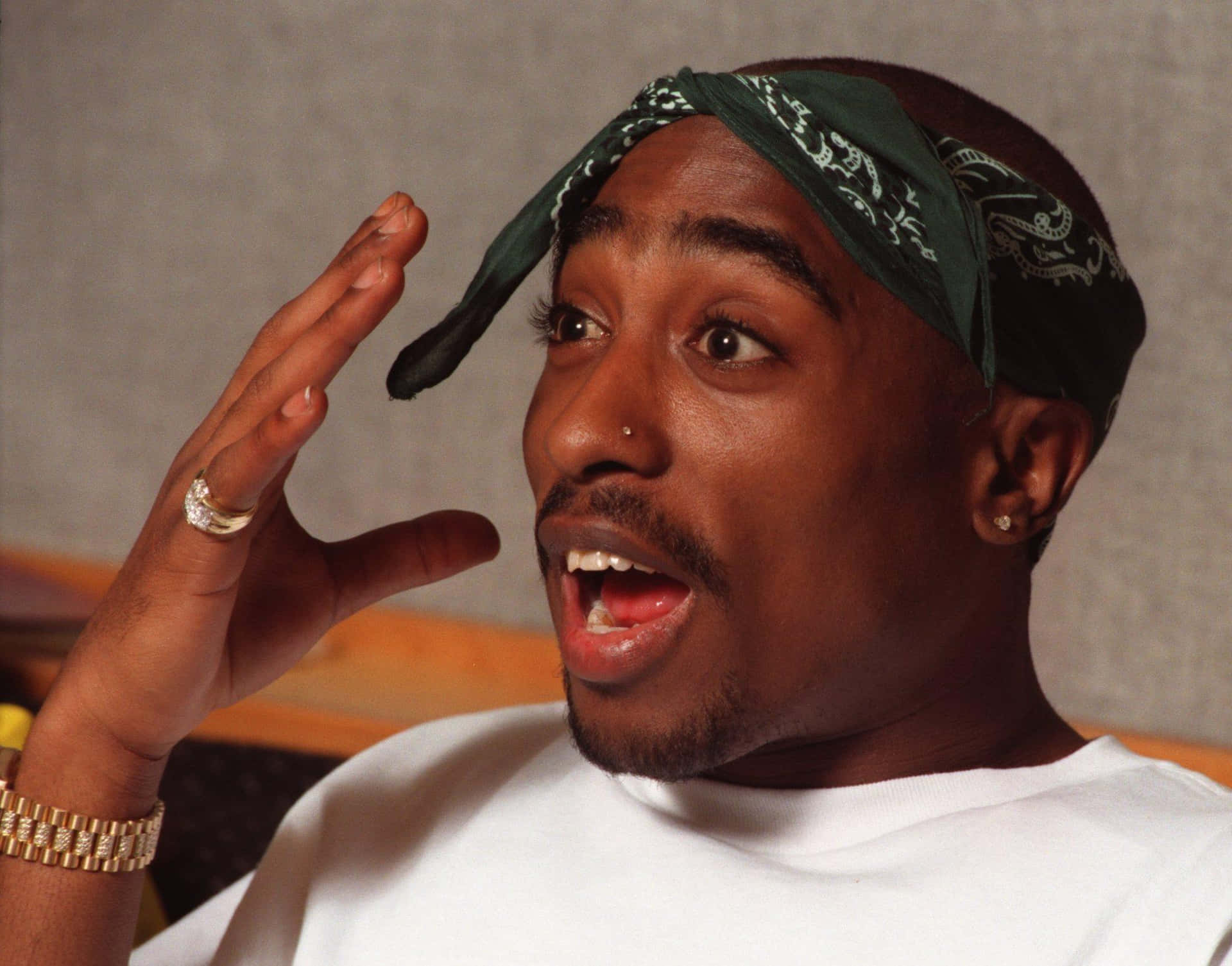 tupac 桌布 壁紙 — Tupac Shakur 戴著綠色頭巾和金飾，做出富有表現力的驚訝表情。