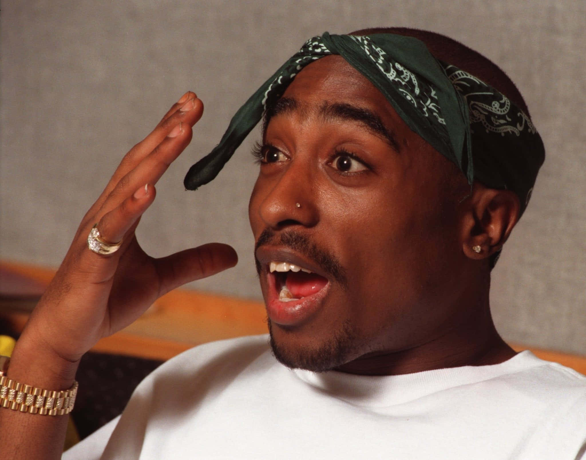 桌布 壁紙 — Tupac Shakur 戴著綠色頭巾和金飾，做出驚訝的表情，手舉起。