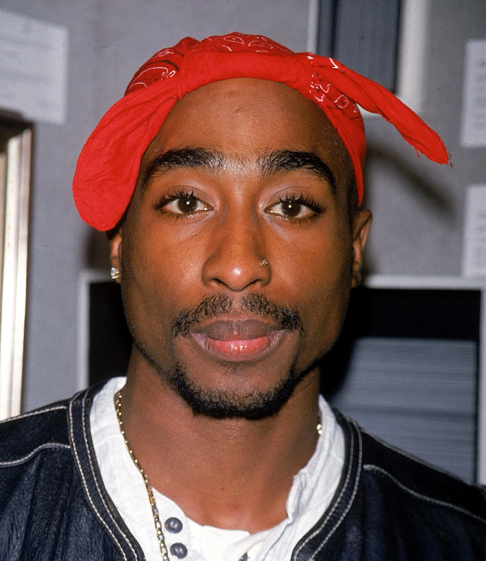 tupac 桌布 壁紙 — Tupac Shakur 的特寫肖像，戴著紅色頭巾和牛仔外套，表情嚴肅。