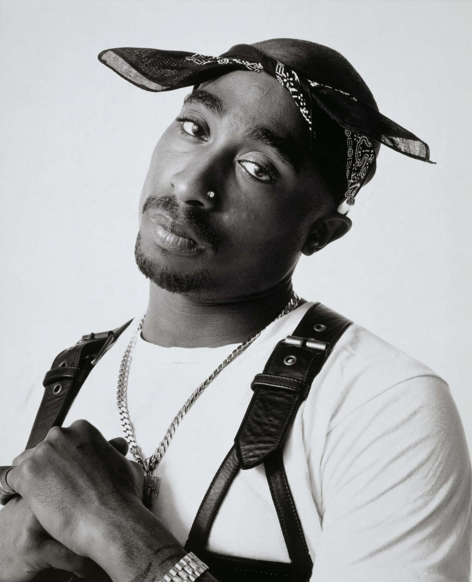 Tupac Shakur 的黑白肖像，戴著頭巾帽和皮革吊帶。 — Tupac GIF 壁紙
