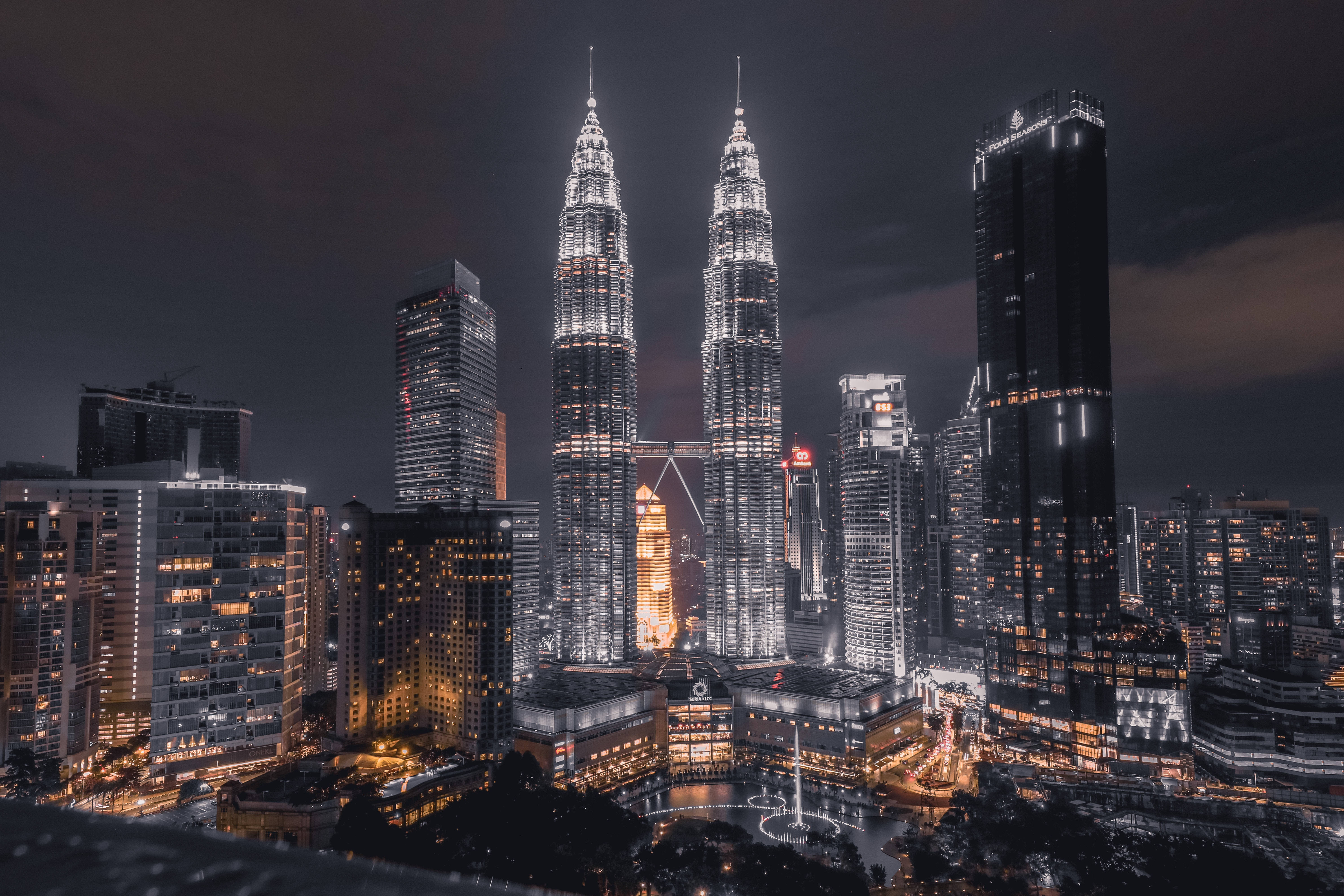 X 桌布 壁紙 — Twin skyscrapers pierce the night sky above a glittering urban skyline with illuminated windows and glowing streets below.