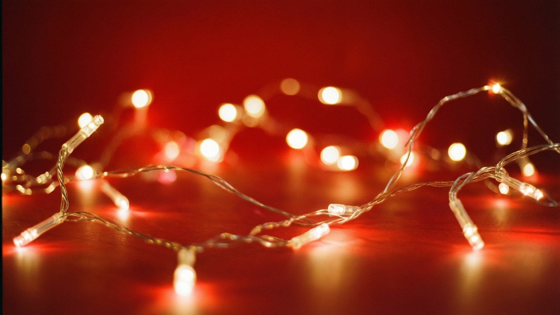 Twinkling Lights Red 壁紙 — 閃爍的串燈在深紅色背景上溫暖地發光，帶有柔和的散景亮點。
