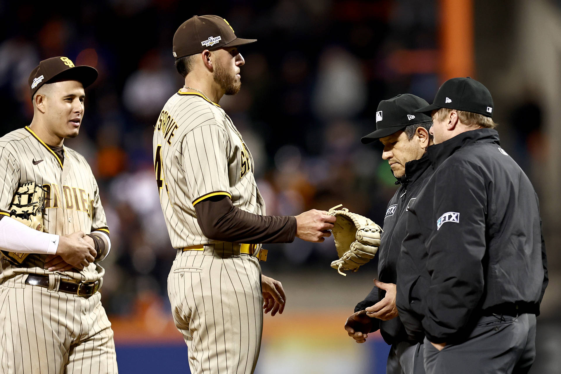 棒球運動員和裁判在夜間燈光球場上互動。 — MLB 壁紙