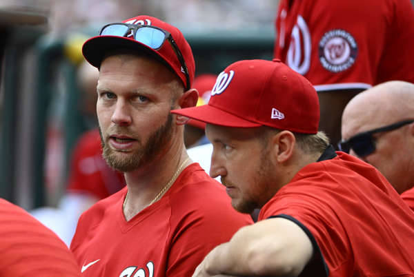 兩名身穿紅色球衣的棒球運動員在比賽期間坐在球員休息區。 — MLB 壁紙