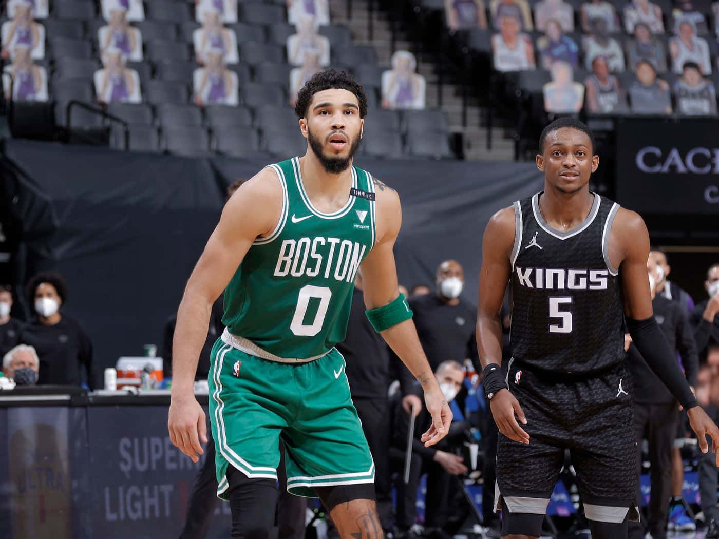 兩名身穿綠色和黑色球衣的NBA籃球運動員在比賽中站在球場上。 — NBA 壁紙