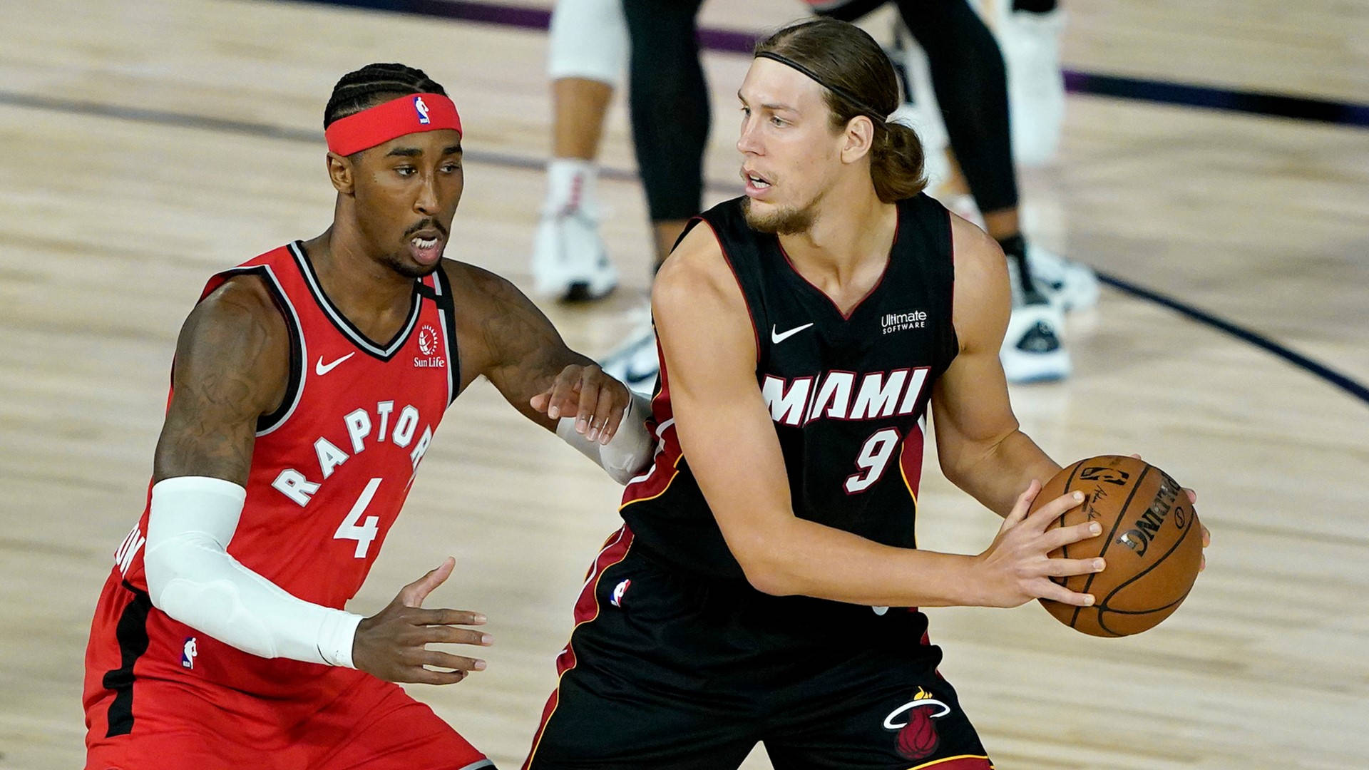 兩名NBA籃球運動員在比賽中行動，一人防守，另一人運球。