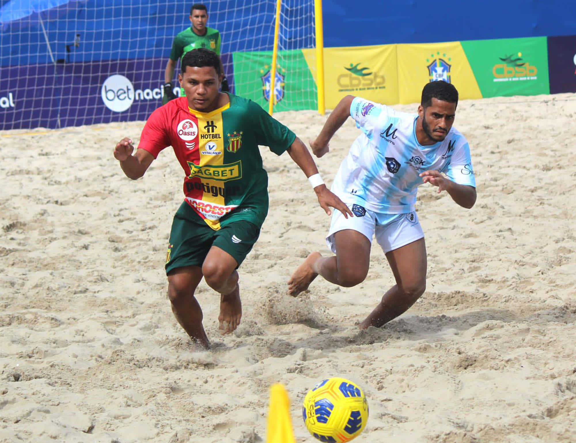 Beach Soccer 桌布 壁紙 — 兩名沙灘足球運動員在陽光普照的沙灘上，於球門附近激烈爭奪一個黃色足球。