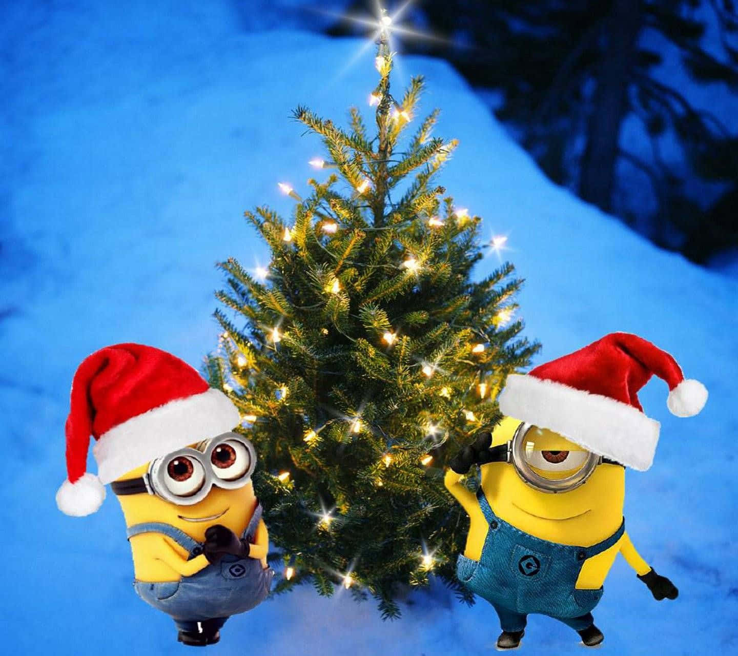  壁紙 — 兩個戴著聖誕帽的節日Minions，愉快地在一個被雪覆蓋、閃爍著溫暖燈光的聖誕樹旁擺姿勢。