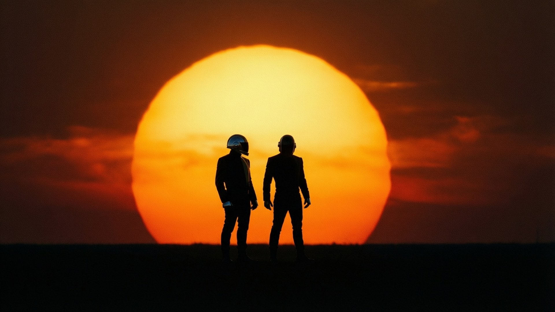 Silhouette Sunset Duo 壁紙 — 兩個戴頭盔的人物在日落時分以剪影形式站在一個巨大的橙色太陽前。