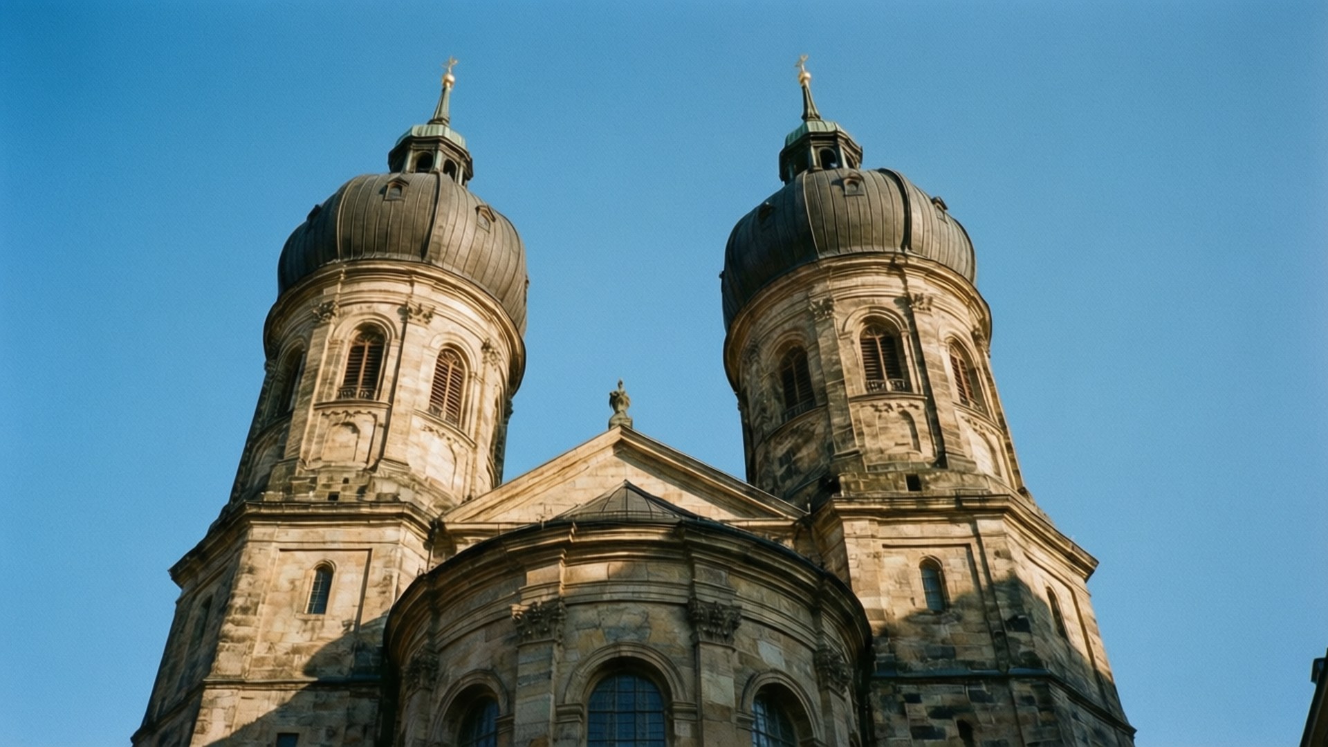 Frauenkirche Towers 壁紙 — 兩座宏偉的石造圓頂塔樓在清澈的藍天下聳立，在歷史悠久的教堂外牆上投下銳利的陰影。