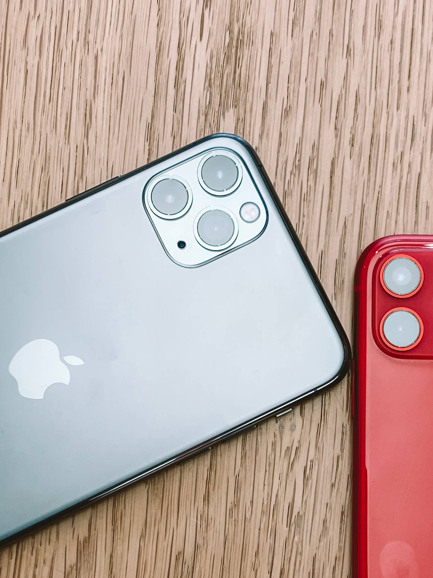 木質表面上的兩支銀色和紅色Apple iPhone — iPhone 11 壁紙