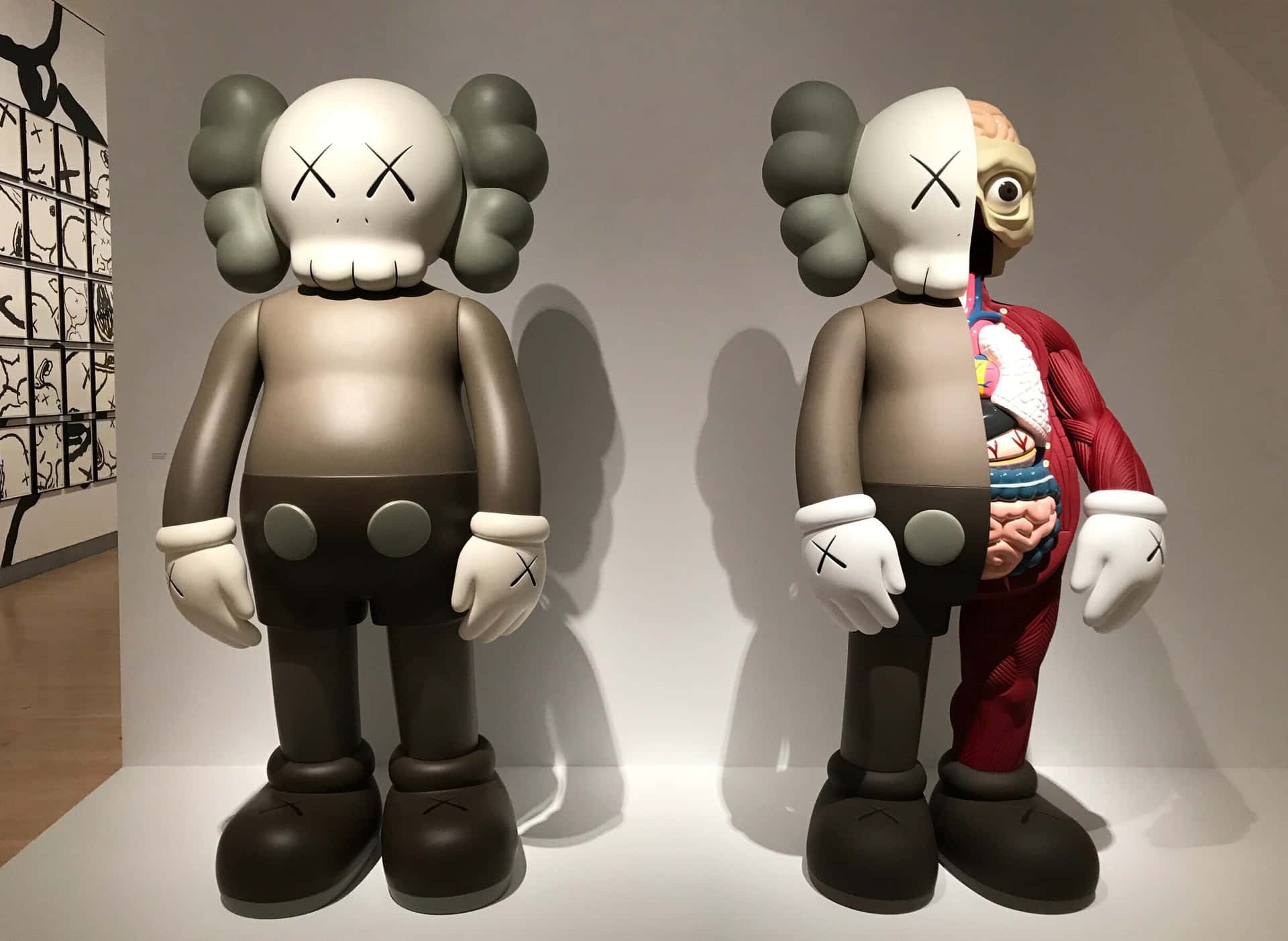 兩件KAWS雕塑，一件完整，一件被切開在畫廊中展示內部器官。 — Kaws 壁紙