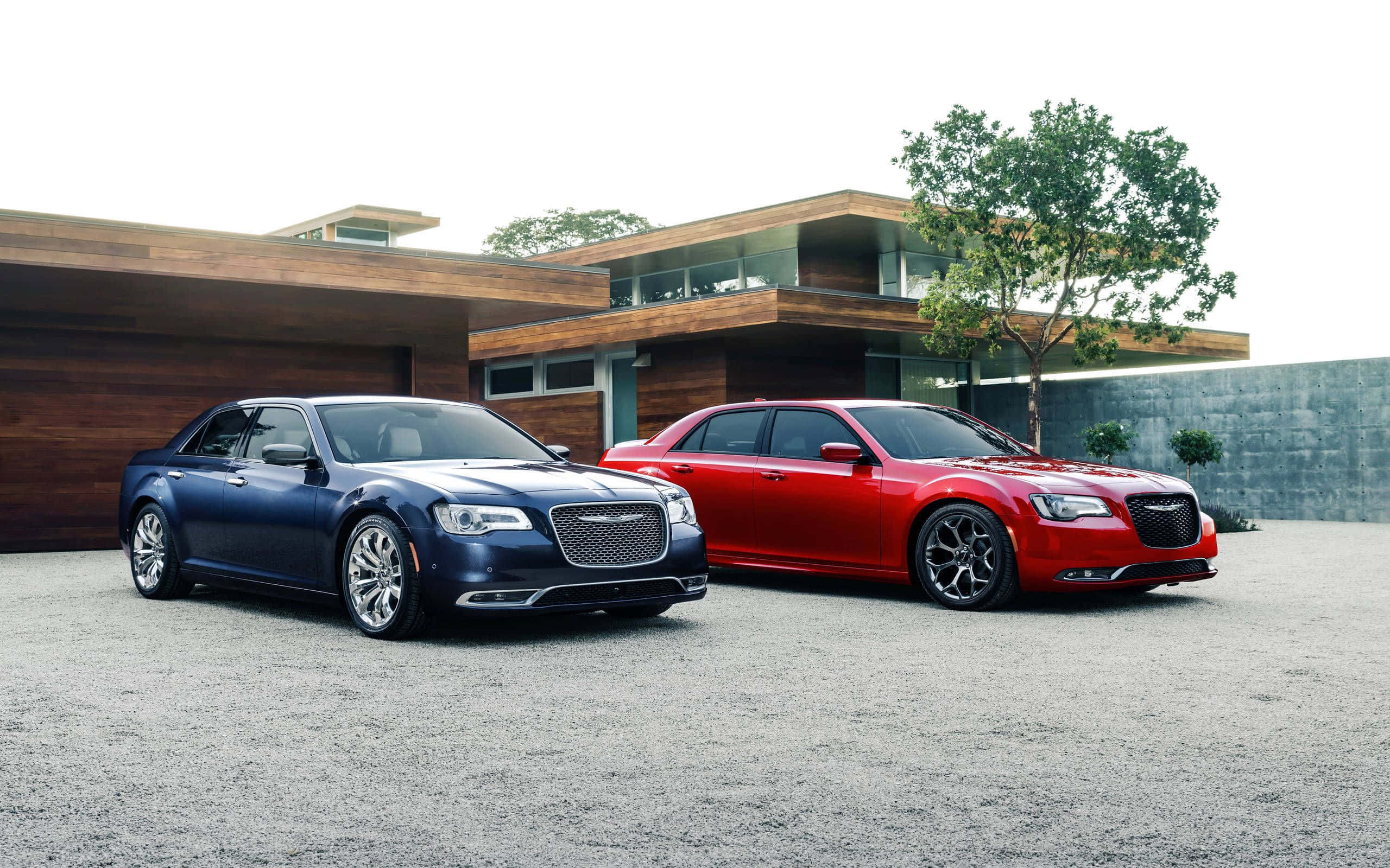 Chrysler 300 桌布 壁紙 — 兩輛豪華轎車，一藍一紅，停在現代木屋前的礫石上，木屋有玻璃陽台。