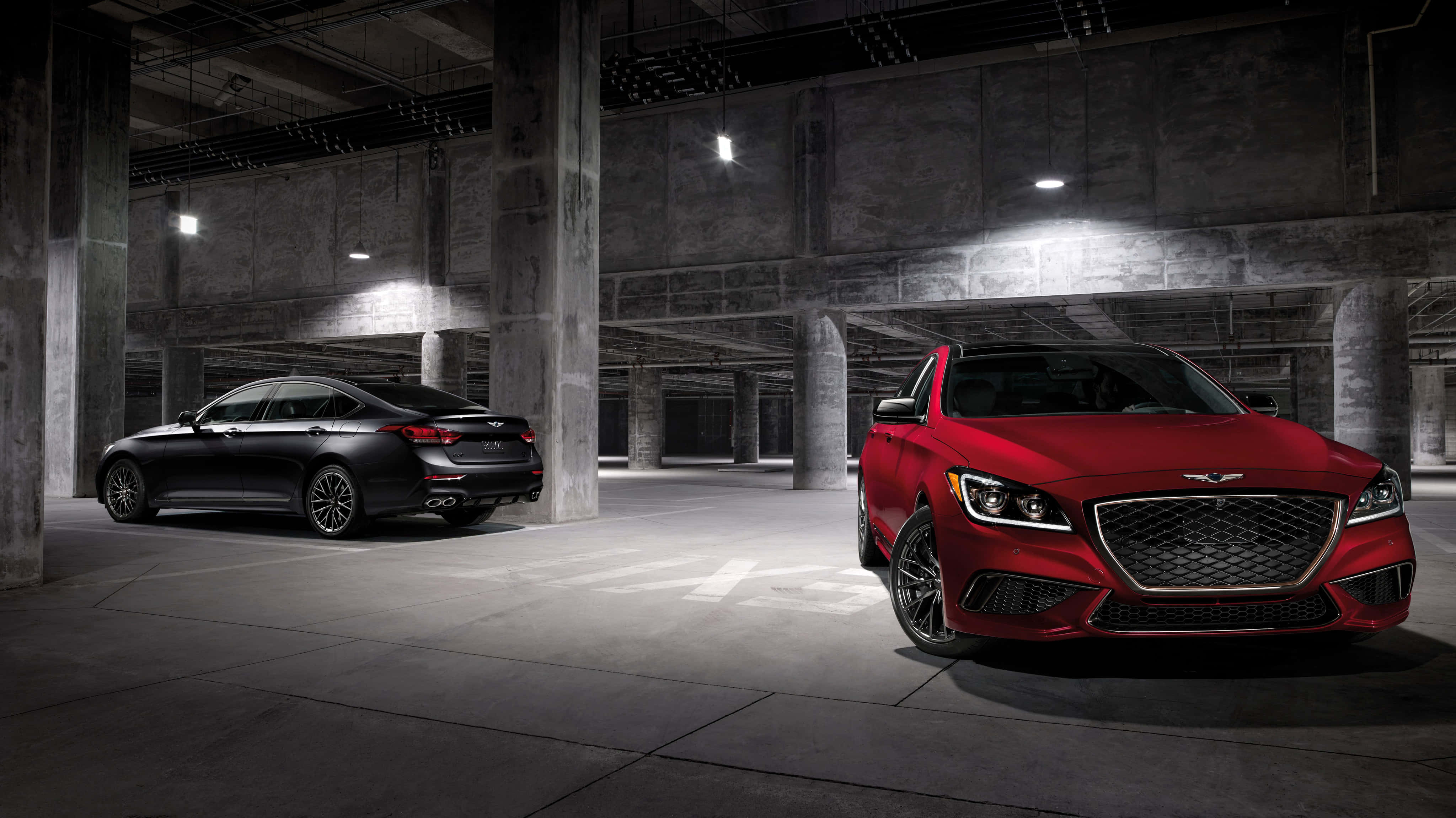 Genesis G80 桌布 壁紙 — 兩輛豪華轎車，一紅一黑，停放在光線昏暗的混凝土地下車庫，帶有工業橫樑和聚光燈。