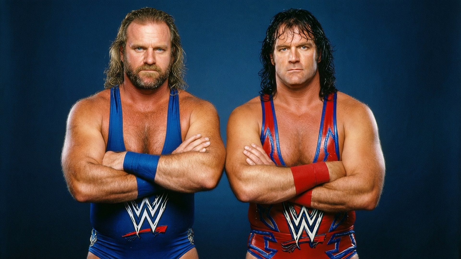 Tag Team Titans 壁紙 — 兩位肌肉發達的WWE摔角手並肩站立，雙臂交叉，背景為深藍色攝影棚。