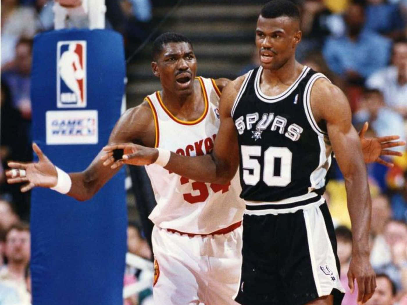 兩位籃球運動員在比賽中爭吵，背景有觀眾。 — NBA 壁紙