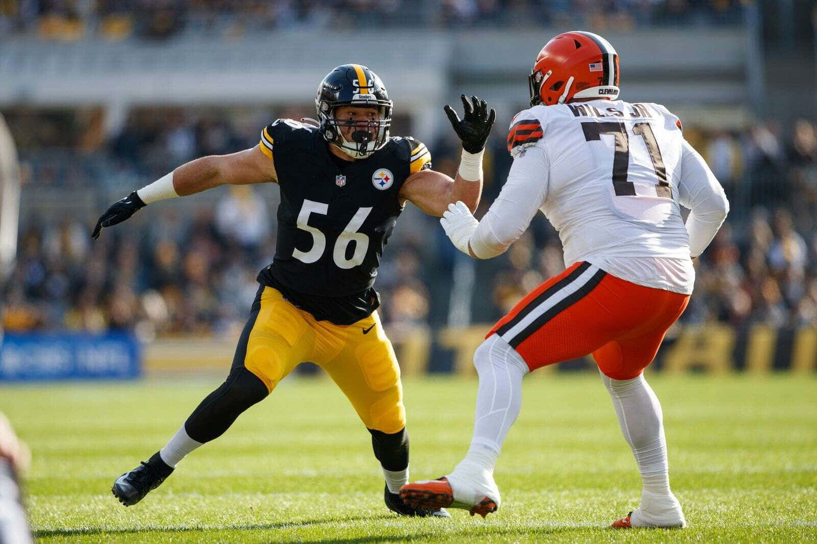  壁紙 — 兩名NFL球員，身穿黑色和黃色對比白色和橙色，在陽光明媚的綠色球場上激烈攔截。