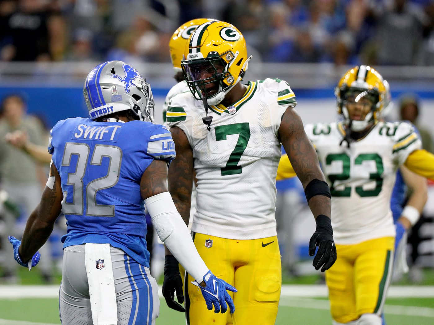  壁紙 — 兩名身穿藍色和綠色球衣的NFL球員在明亮的體育場上對峙。