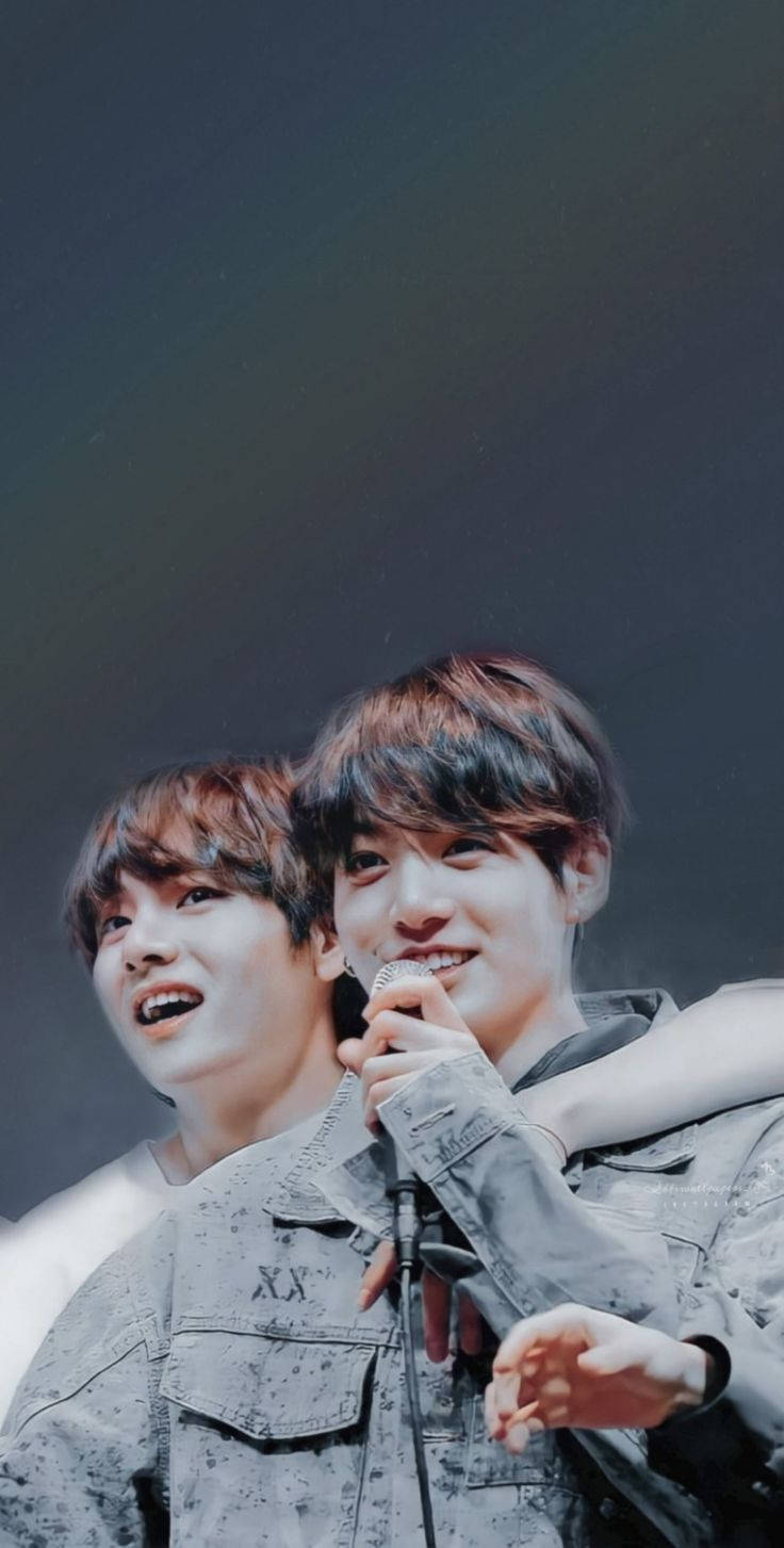 兩位年輕男表演者在演唱會期間於舞台上燦爛微笑。 — Jungkook 壁紙