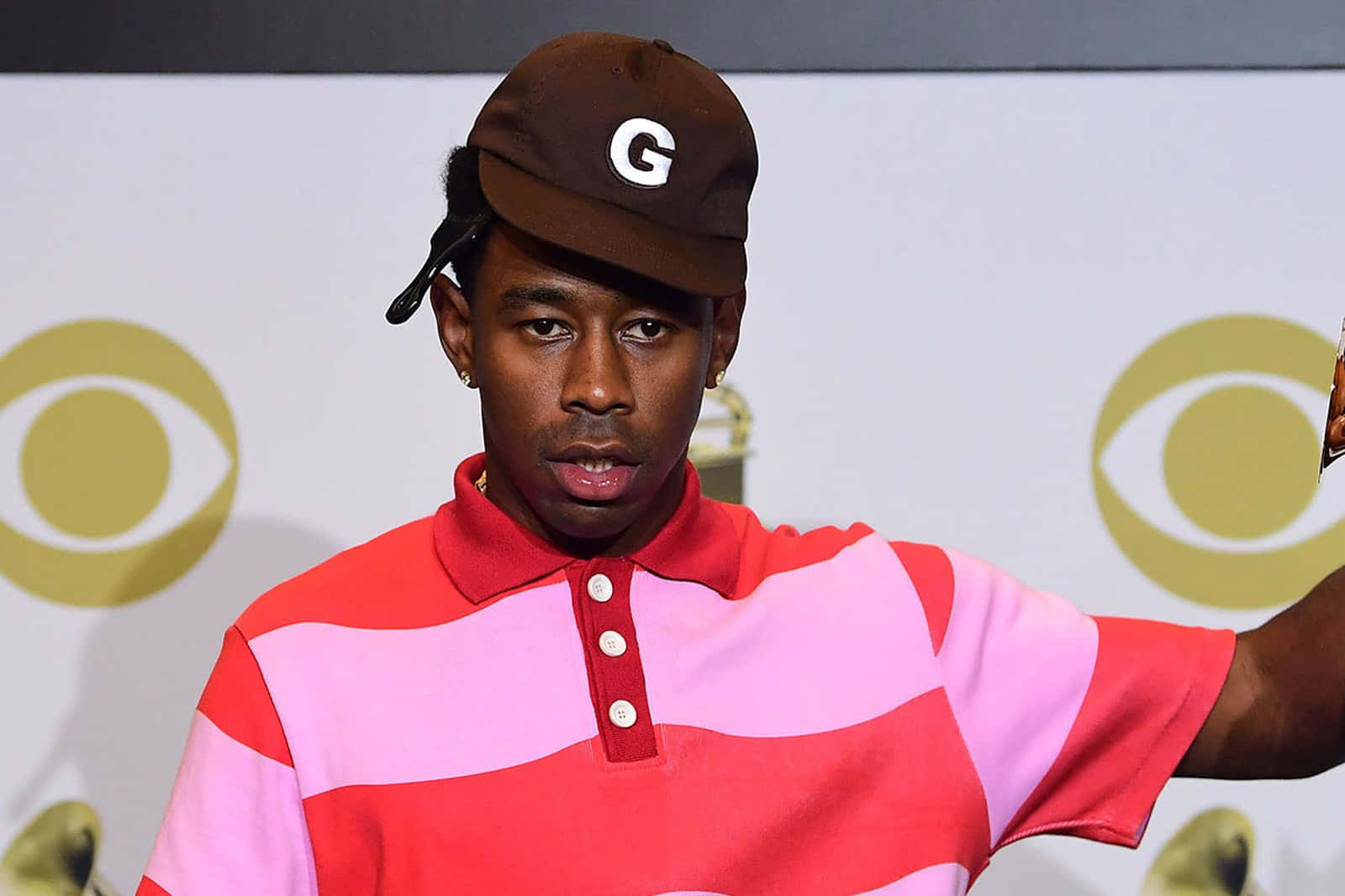 Rappers 桌布 壁紙 — Tyler The Creator 在CBS活動中戴著一頂帶有白色G標誌的棕色帽子，穿著紅粉條紋Polo衫。