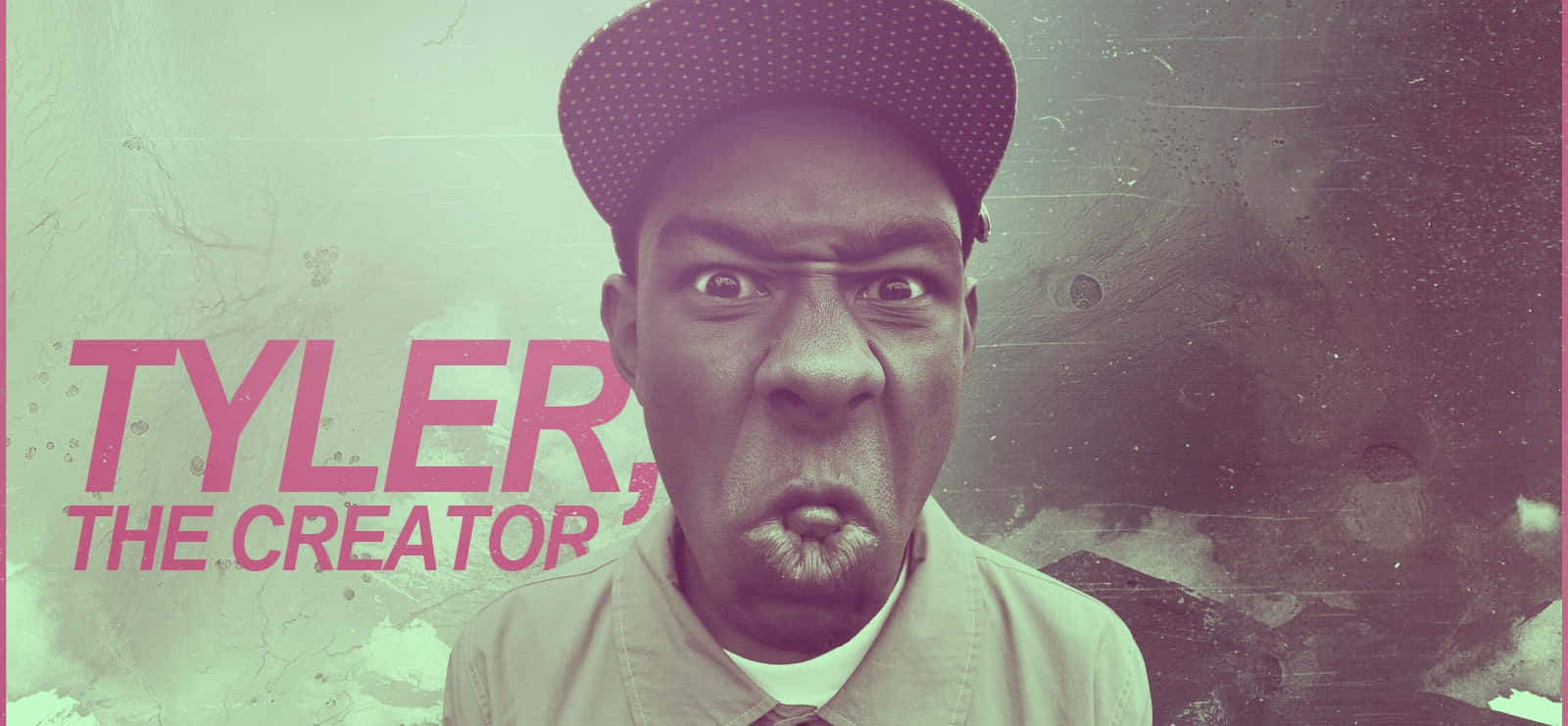 Creator 桌布 壁紙 — Tyler the Creator 在帶有紋理的粉紅色和綠色背景前，睜大眼睛、噘起嘴唇，神情專注地凝視。