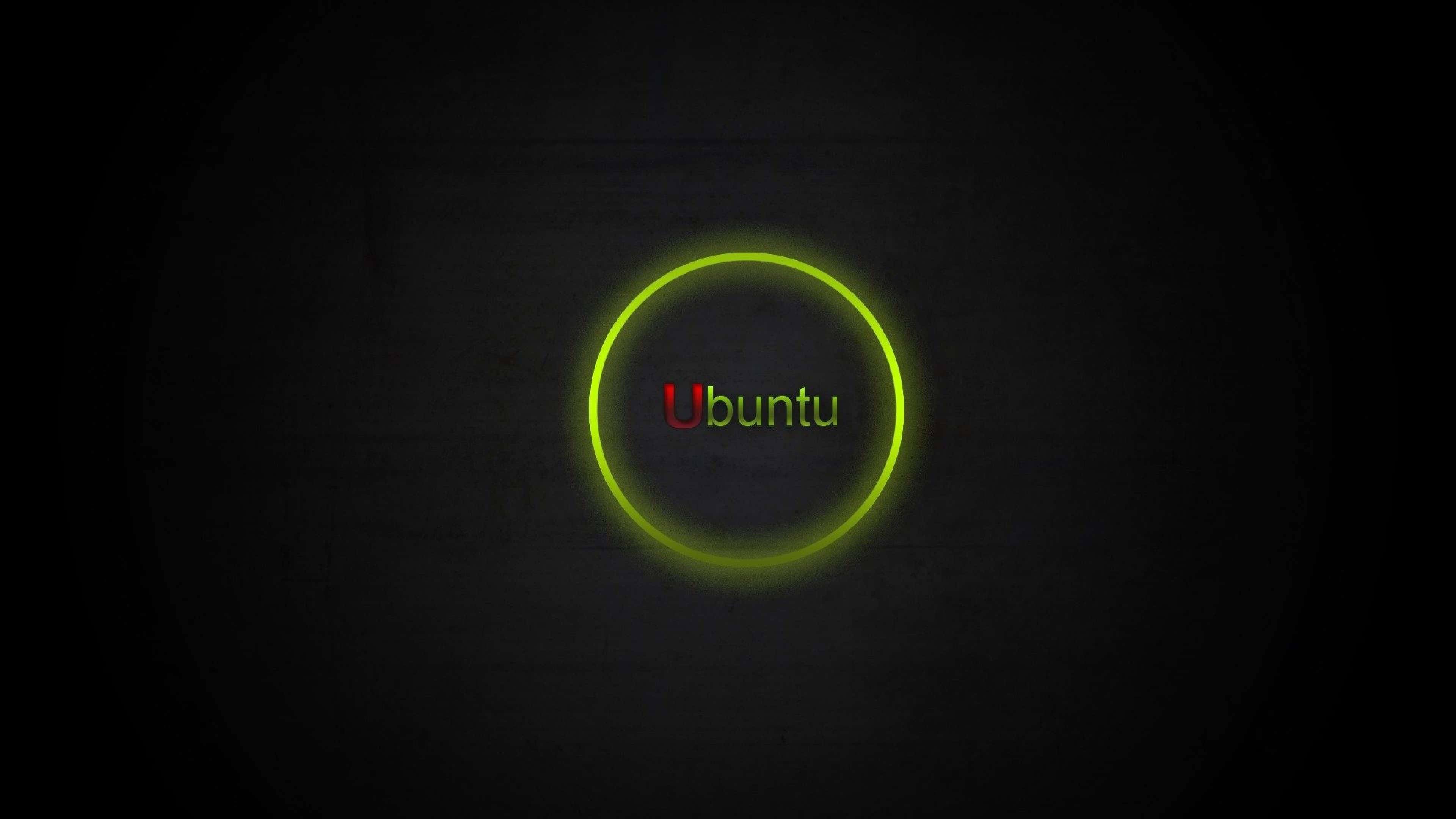 Ubuntu 4K 桌布 壁紙 — Ubuntu 標誌在黑暗紋理背景上的發光圓圈內發出鮮豔的綠色光芒。