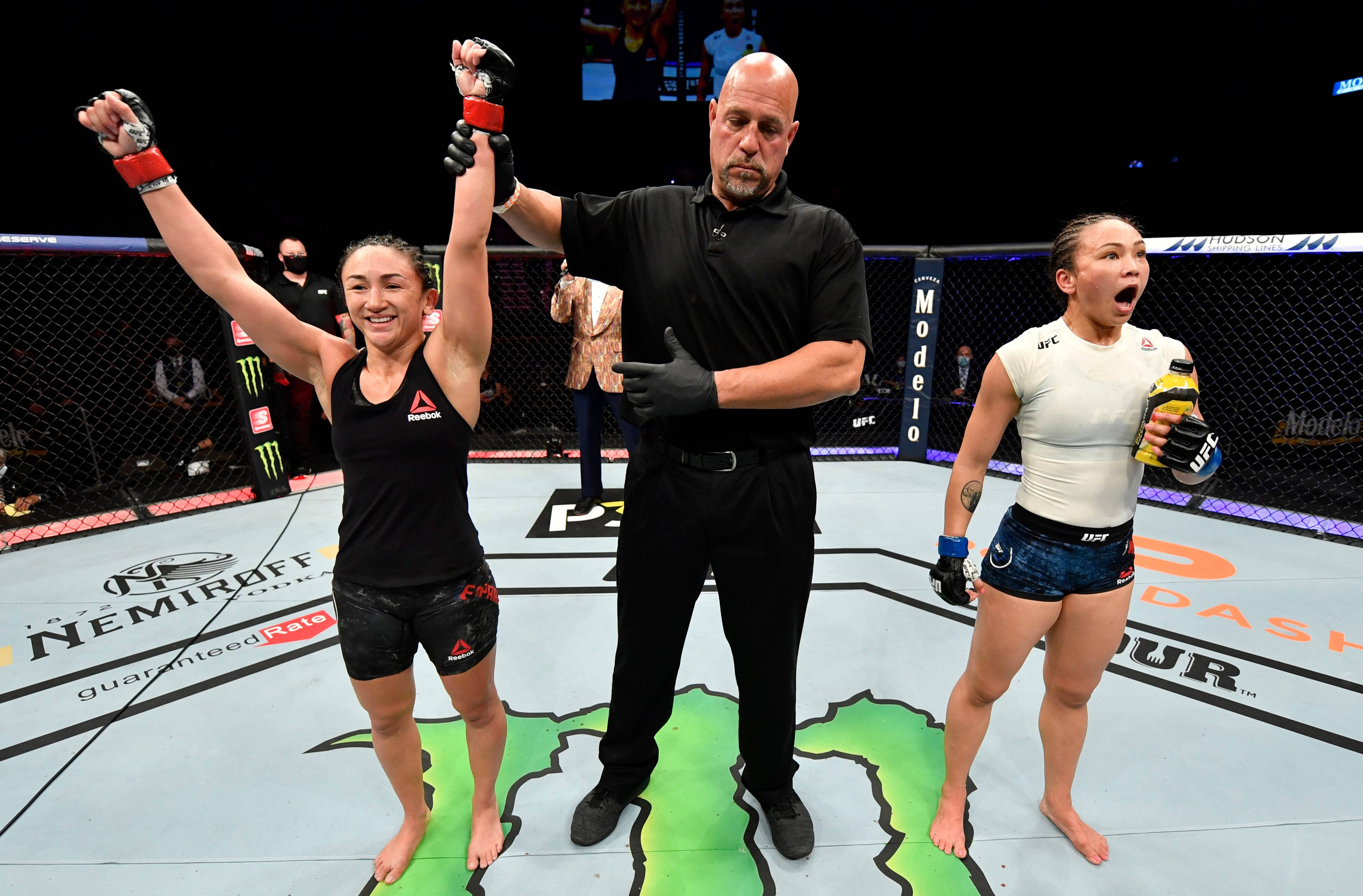 冠軍 桌布 壁紙 — UFC裁判舉起獲勝女拳手的臂，而她的對手在八角籠內震驚反應。
