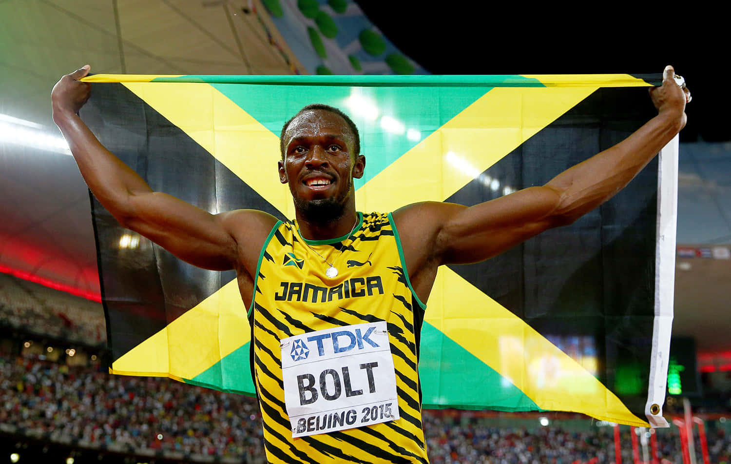 運動 桌布 壁紙 — Usain Bolt 在北京2015年田徑賽事中，在體育館內高舉牙買加國旗，展現勝利光芒。