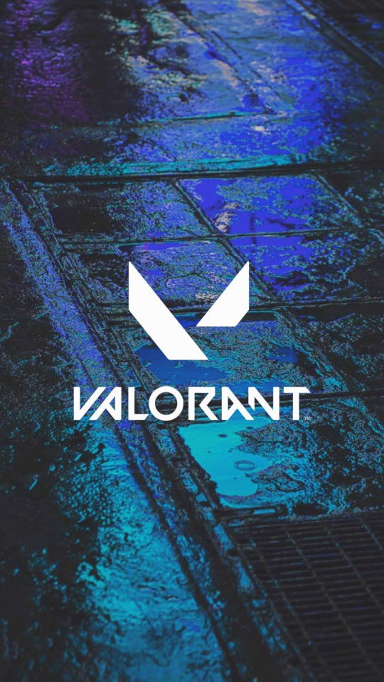 Valorant iPhone 壁紙 桌布 壁紙 — Valorant 標誌在濕漉漉的鵝卵石街道上發出白色光芒，反射出霓虹藍和紫色的燈光。